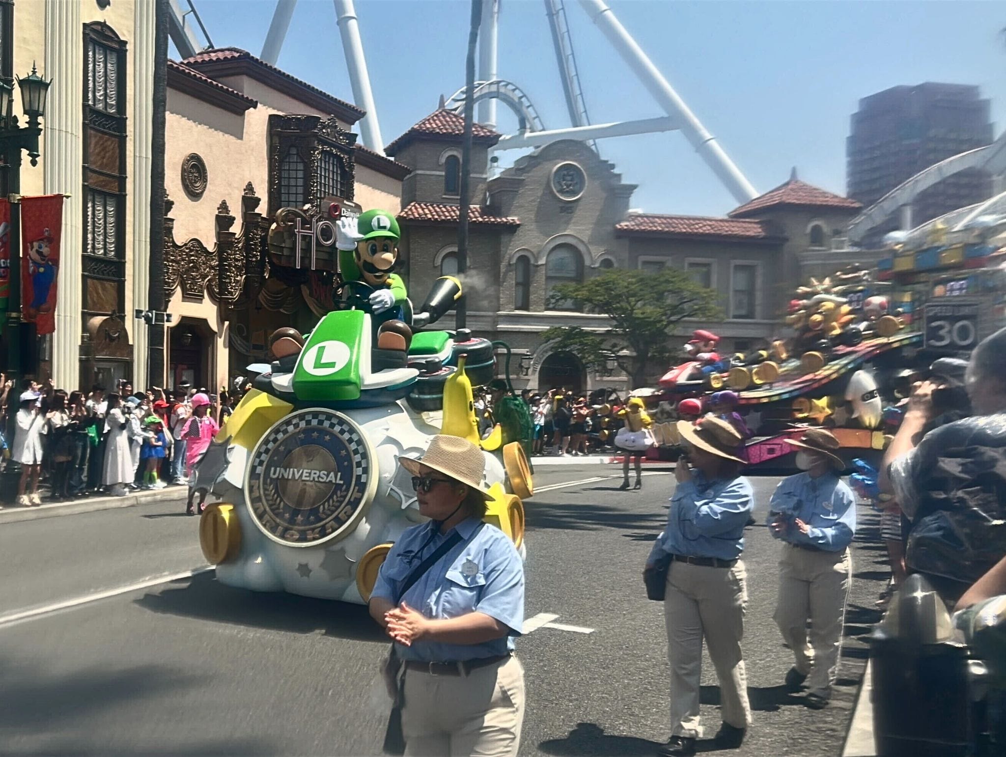 Photos capture the Summer Splash Parade at Universal Studios Japan with a Luigi float and staff in blue shirts.