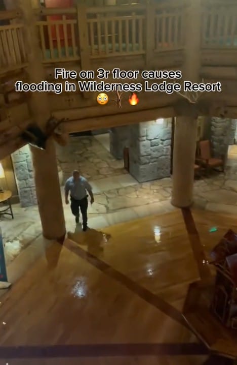 A man walks on a wet wooden floor in Boulder Ridge lobby; text: "Fire on 3rd floor causes flooding in Wilderness Lodge Resort.