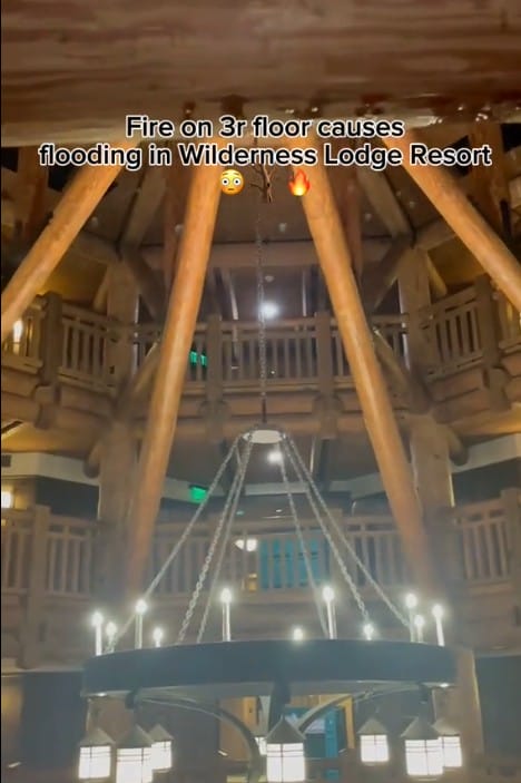 Large wooden lodge interior with boulder ridge balcony railings; text reports fire and flooding at Wilderness Lodge Resort.