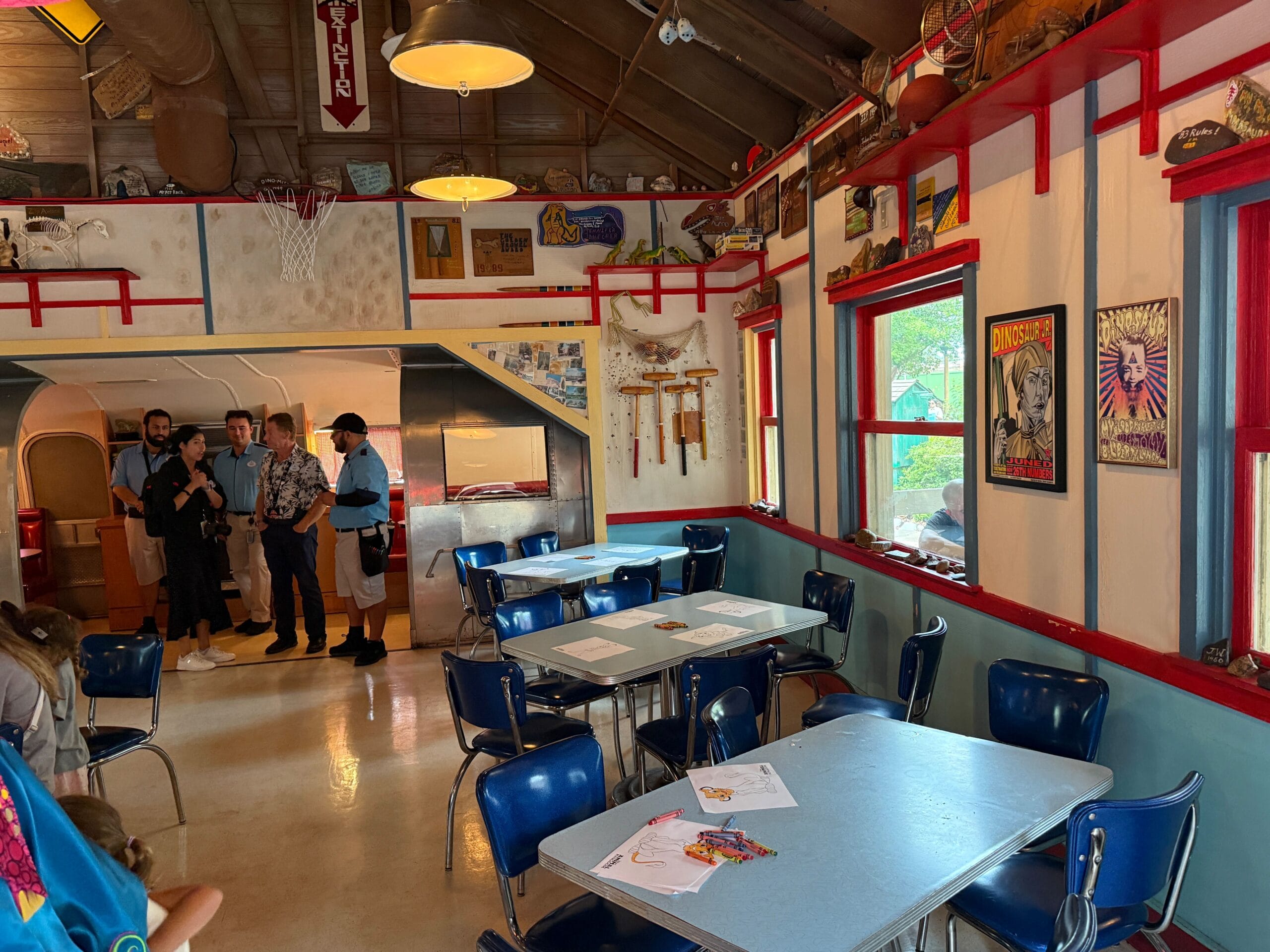 Colorful diner-style room at Daisy's Dig, with blue chairs, wall art, and groups chatting—perfect for fun photos.