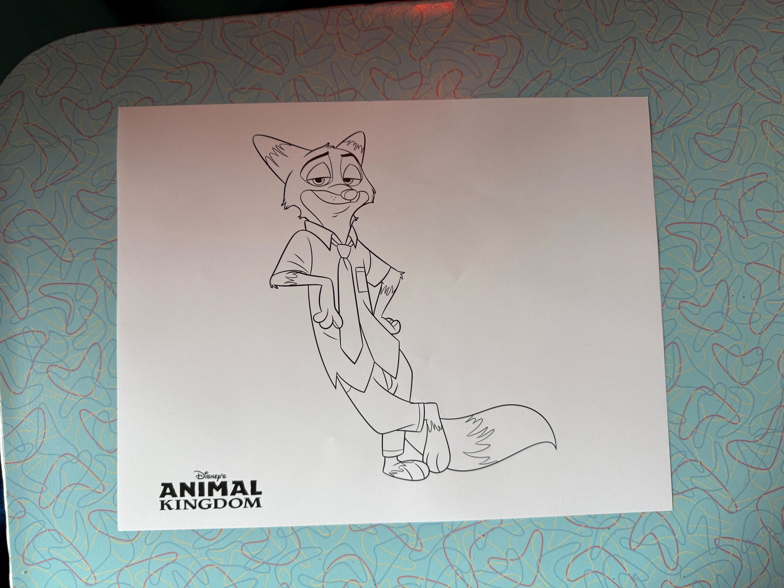 A line drawing of Nick Wilde from Zootopia labeled "Disney Animal Kingdom," on a blue patterned surface; perfect for photos.
