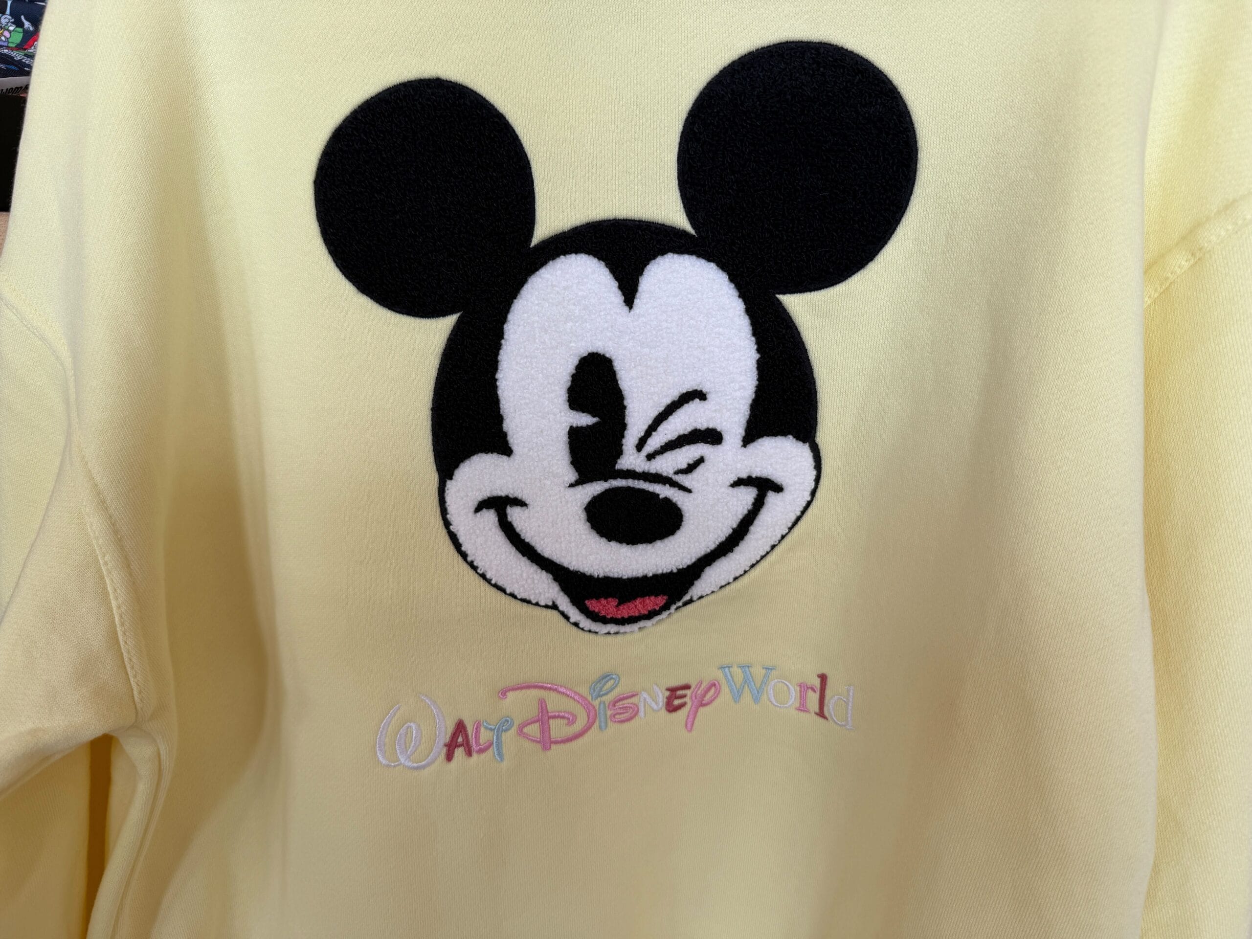 Yellow shirt features a winking Mickey Mouse face and pastel "Walt Disney World" embroidery—perfect for Character Sweatshirts fans.