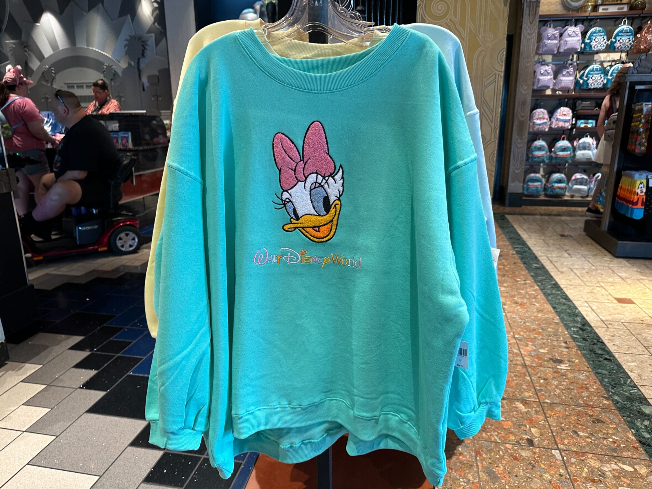 A teal Character Sweatshirt featuring Daisy Duck’s face and pink bow, with "Walt Disney World" embroidered below.