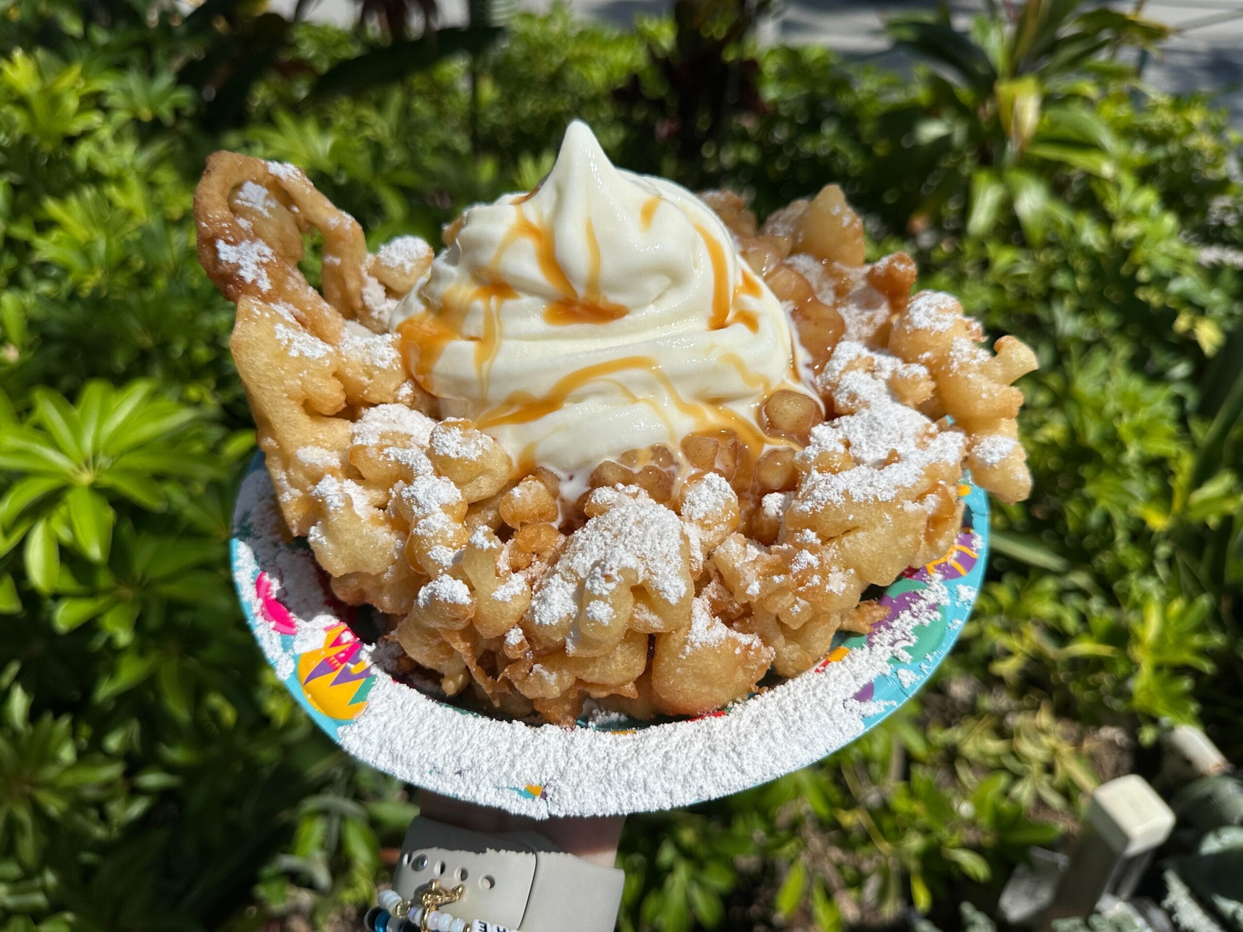Enjoy an Apple Pie Funnel Cake from Epic Eats at Disney's Hollywood Studios, topped with soft serve and caramel sauce.