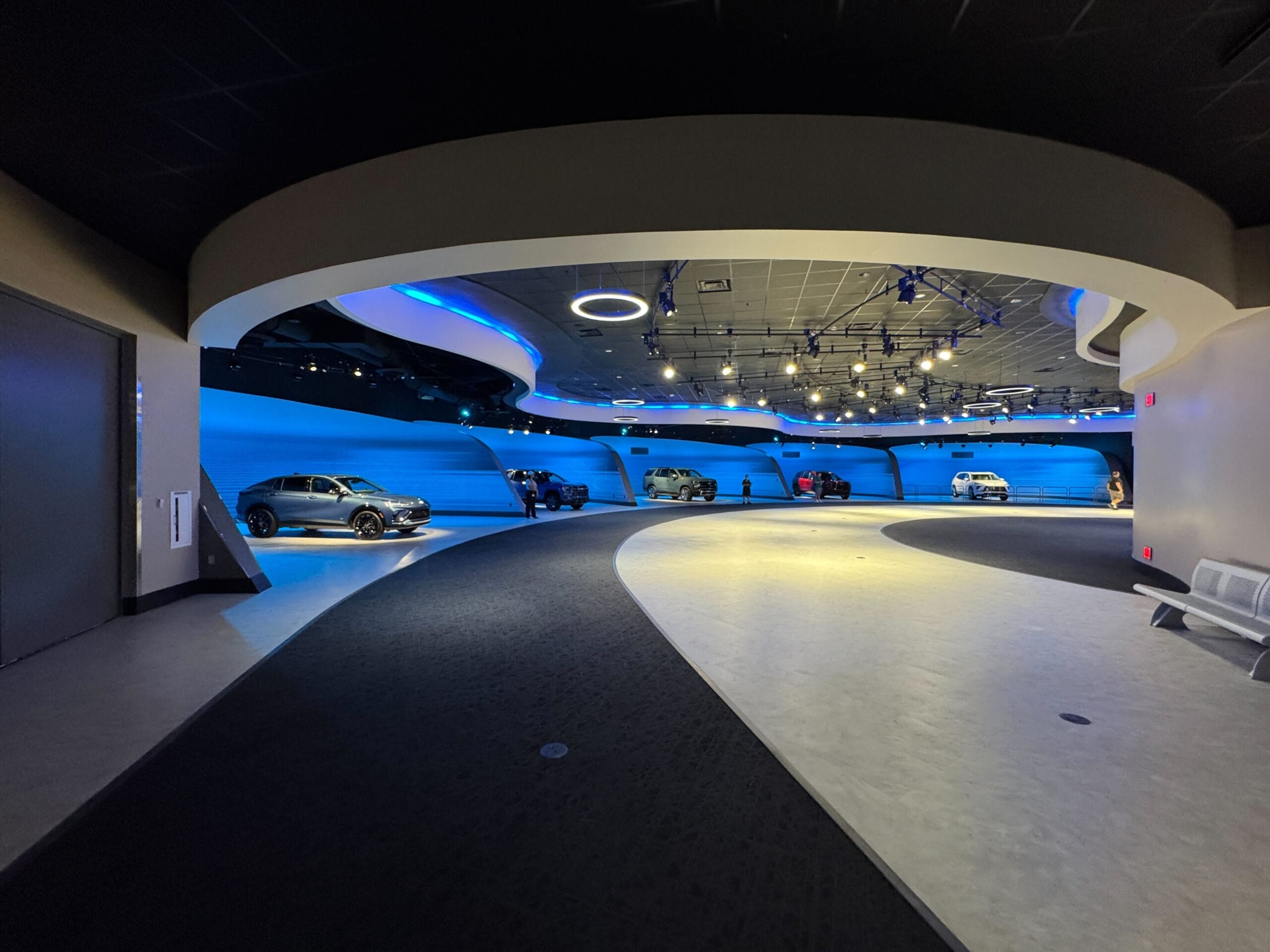Futuristic car showroom featuring Test Track 3.0, blue accent lighting, modern curves—perfect for photos and video.
