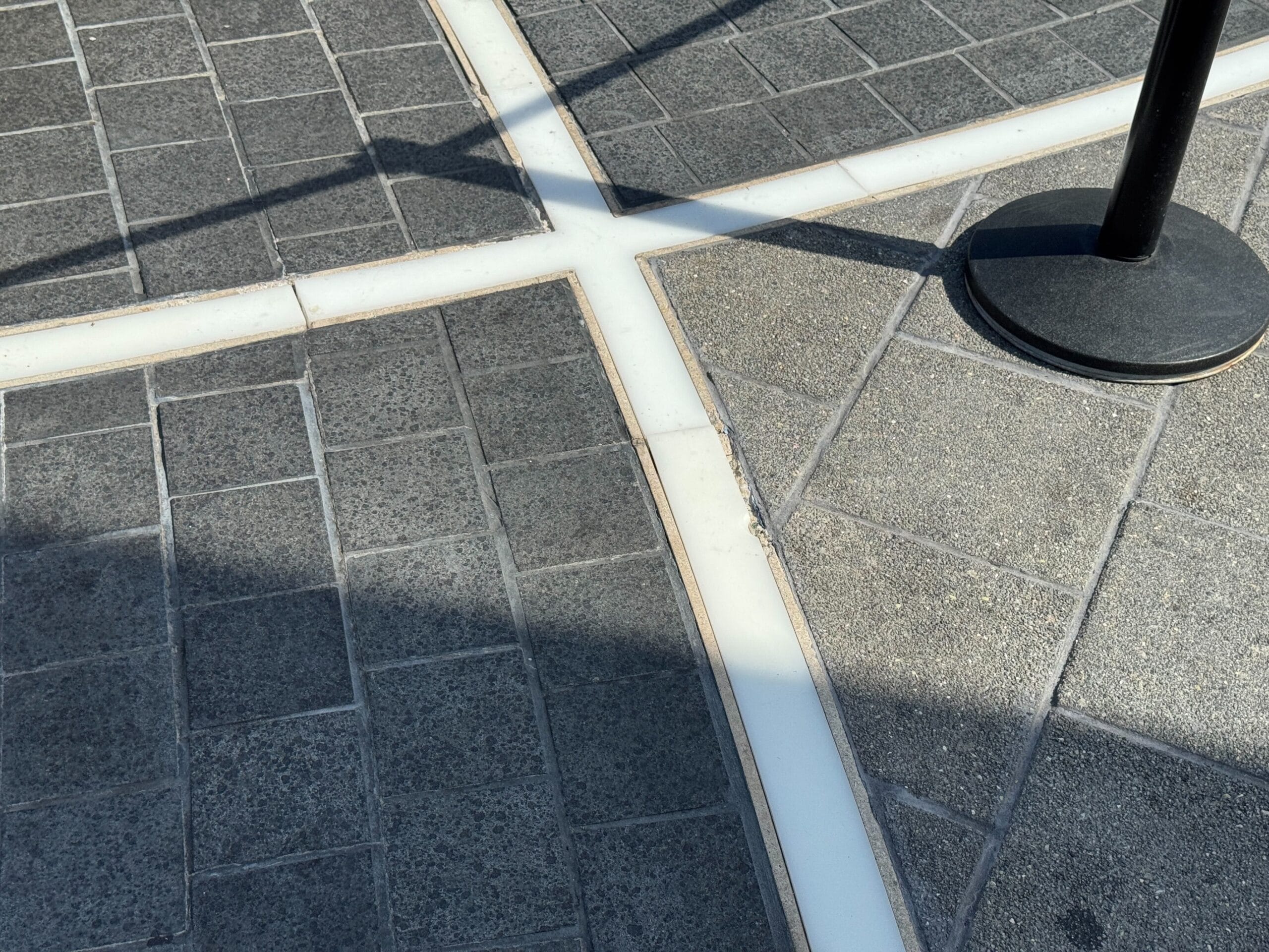 Intersecting white lines divide textured stone tiles; Light-Up Pavement at EPCOT’s World Celebration is visible.