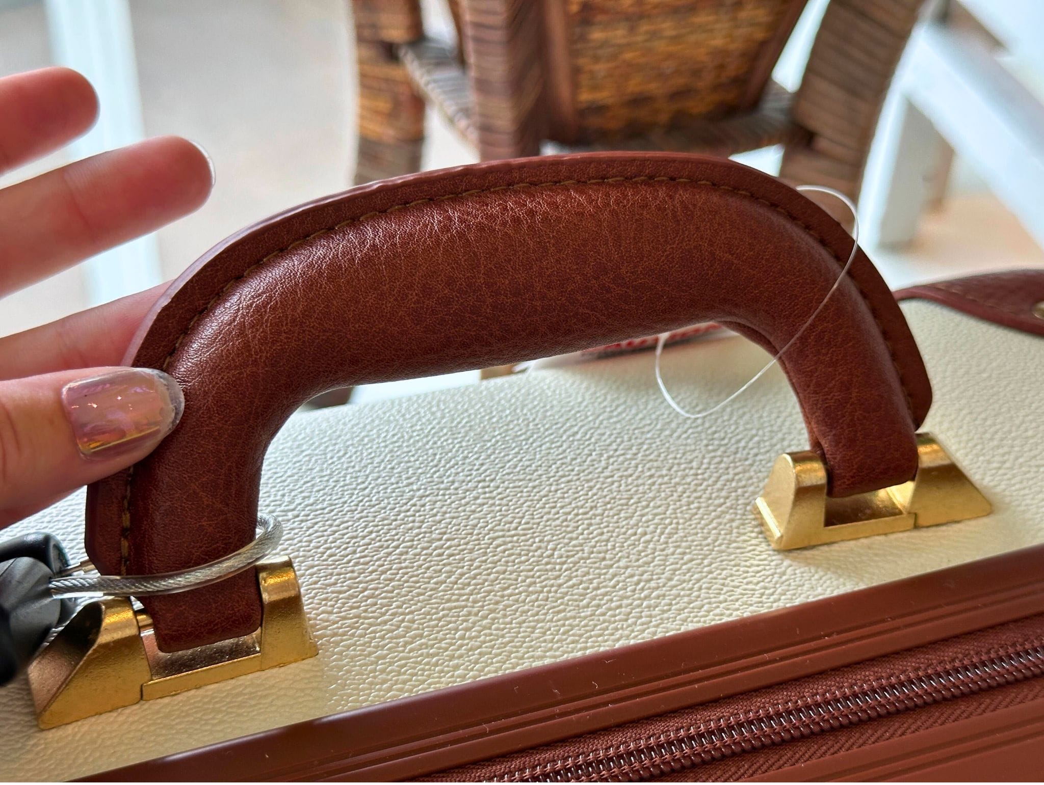 A hand holds a mini luggage bag with gold hardware, like those from Disney Grand Floridian Resort merchandise.