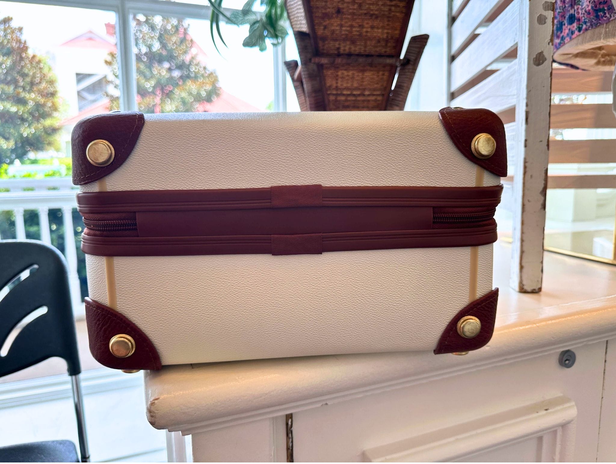 A mini luggage bag with brown trim, inspired by Disney resort merchandise, sits on a white counter indoors.