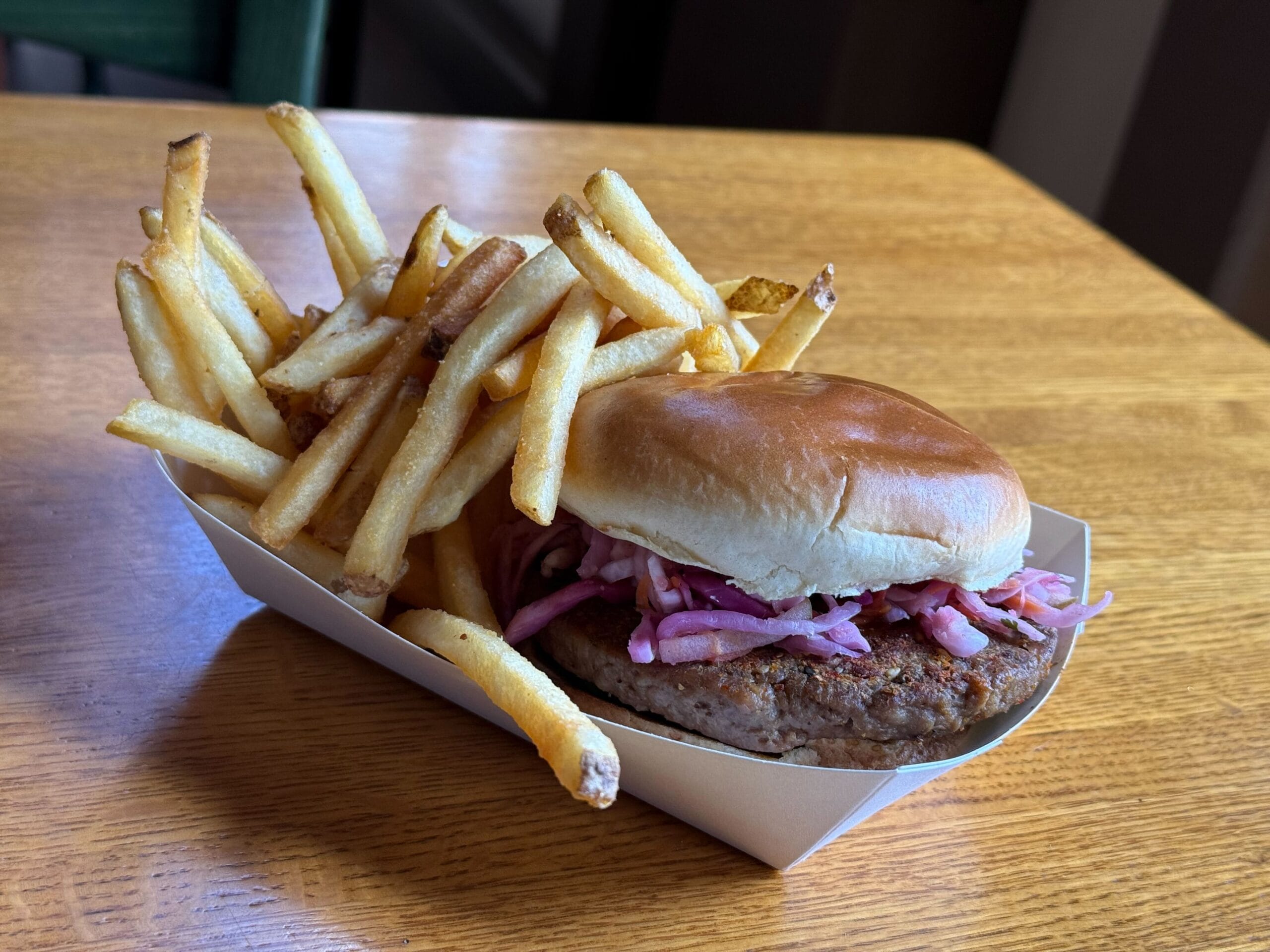 A cardboard tray with fries and a sandwich topped with purple slaw at Disney's Port Orleans Resort.