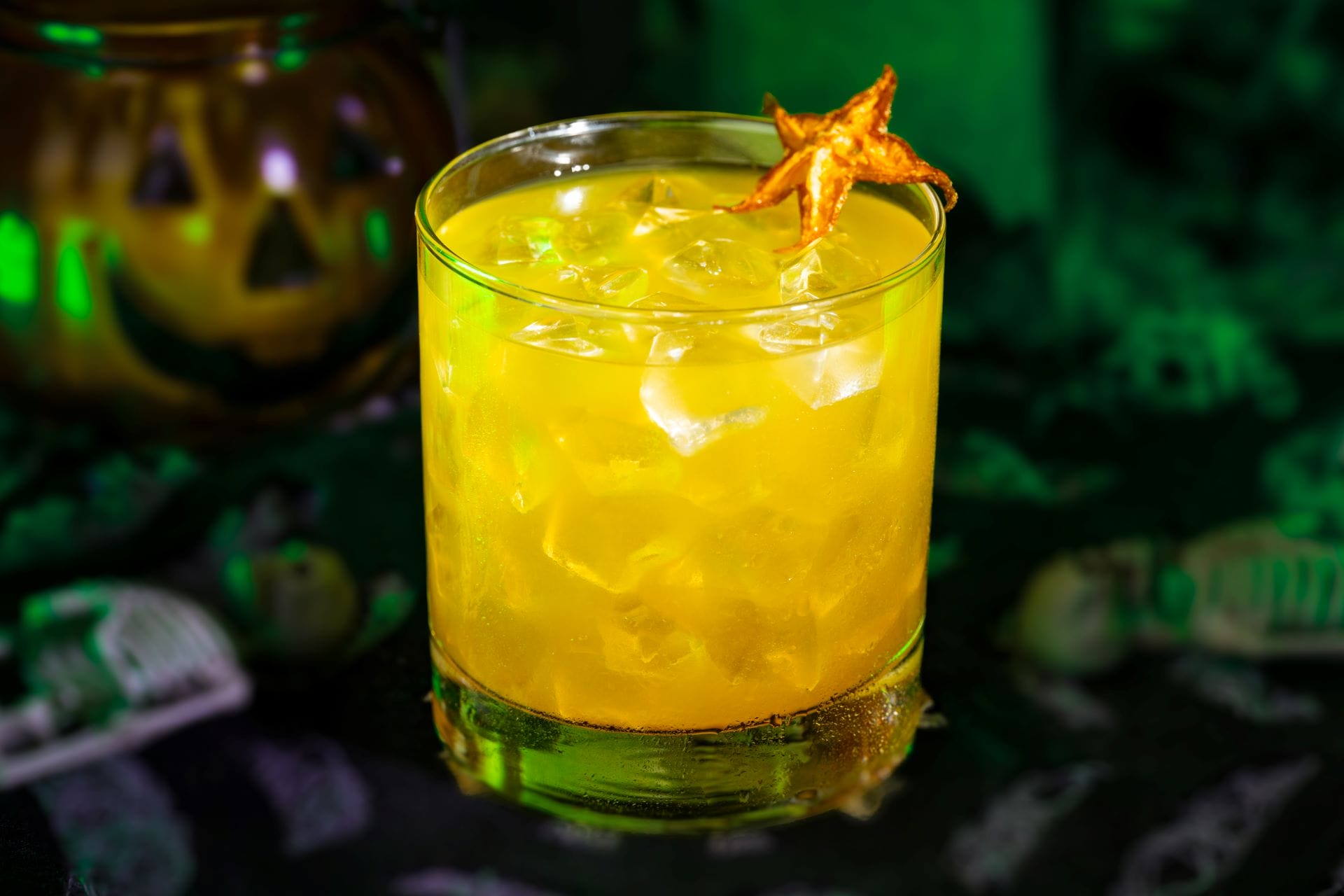 A yellow cocktail with ice and starfruit garnish, inspired by 2025 Mickey’s Not So Scary Halloween Party food and beverages.