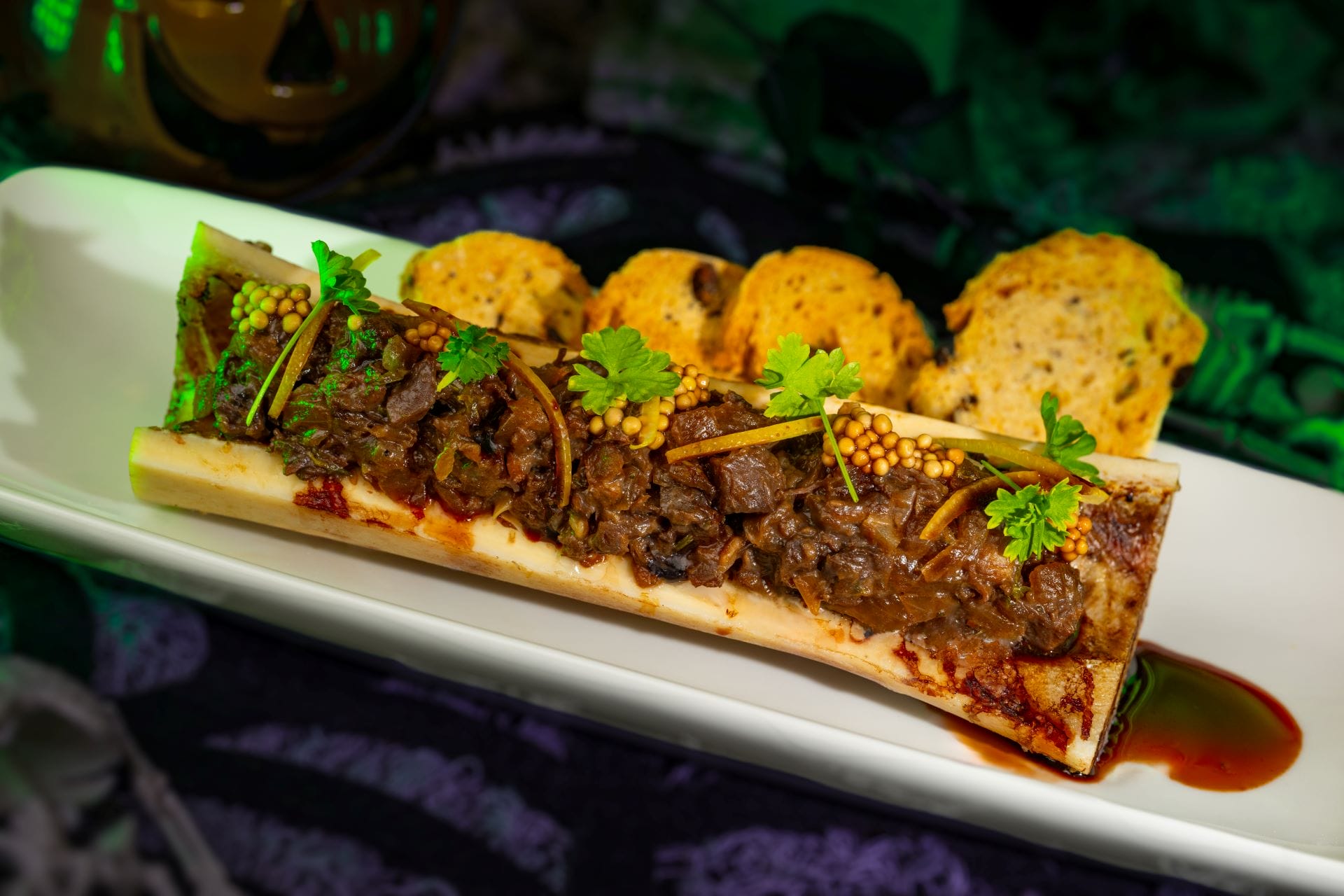 Bone marrow topped with braised beef, mustard seeds, and herbs—a 2025 food and beverages highlight on a white plate.