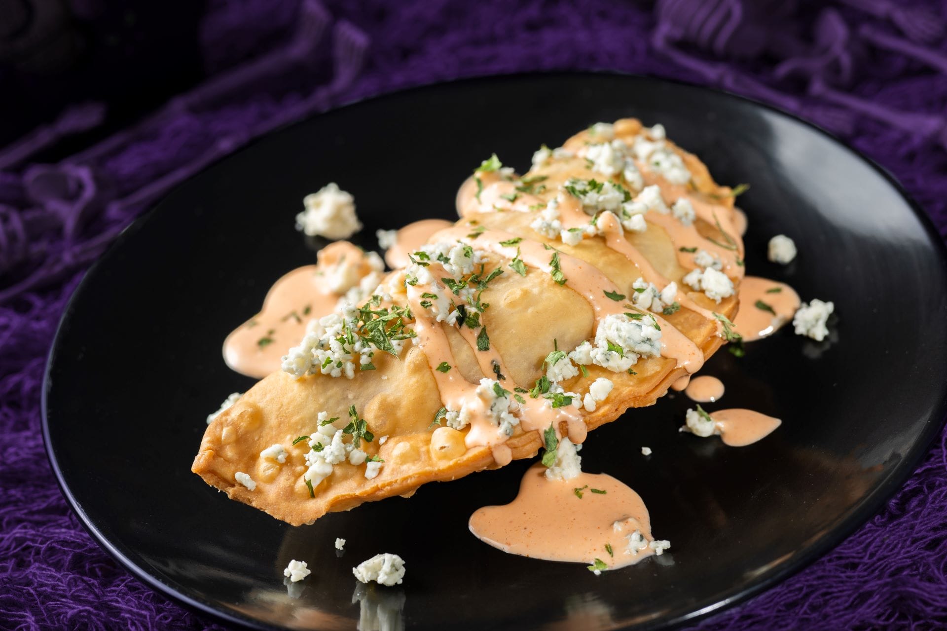 A golden empanada with creamy sauce, herbs, and cheese—a 2025 Food and Beverages treat at Mickey's Not So Scary Halloween Party.