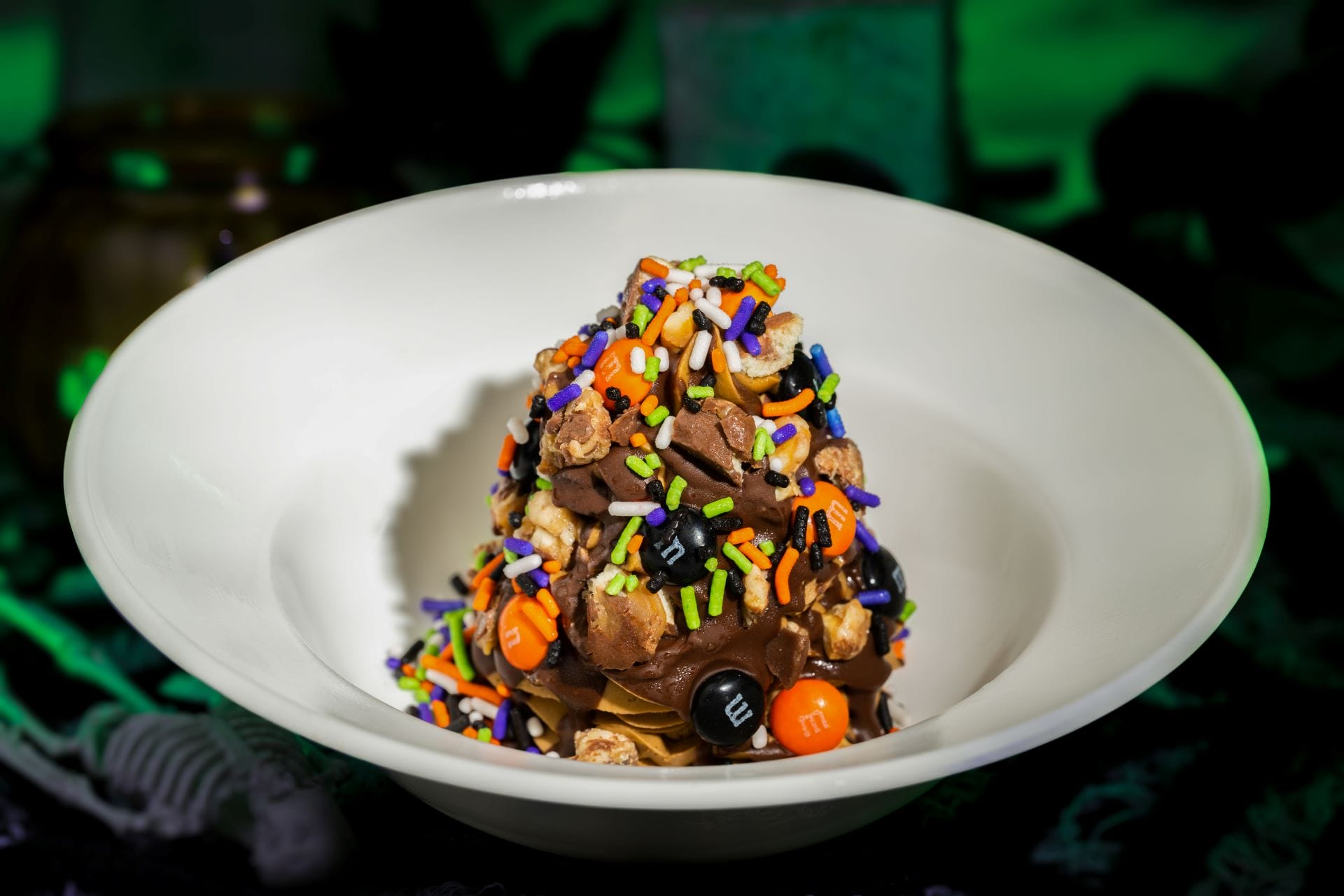 A dessert from Mickey's Not So Scary Halloween Party 2025 is topped with chocolate, sprinkles, and candies in a white bowl.