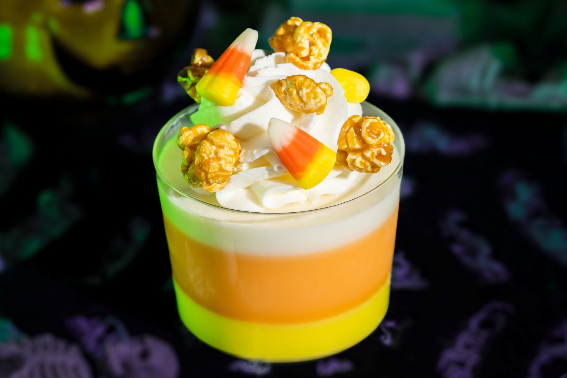 A layered yellow and orange dessert at Mickey's Not So Scary Halloween Party, topped with whipped cream and caramel popcorn.