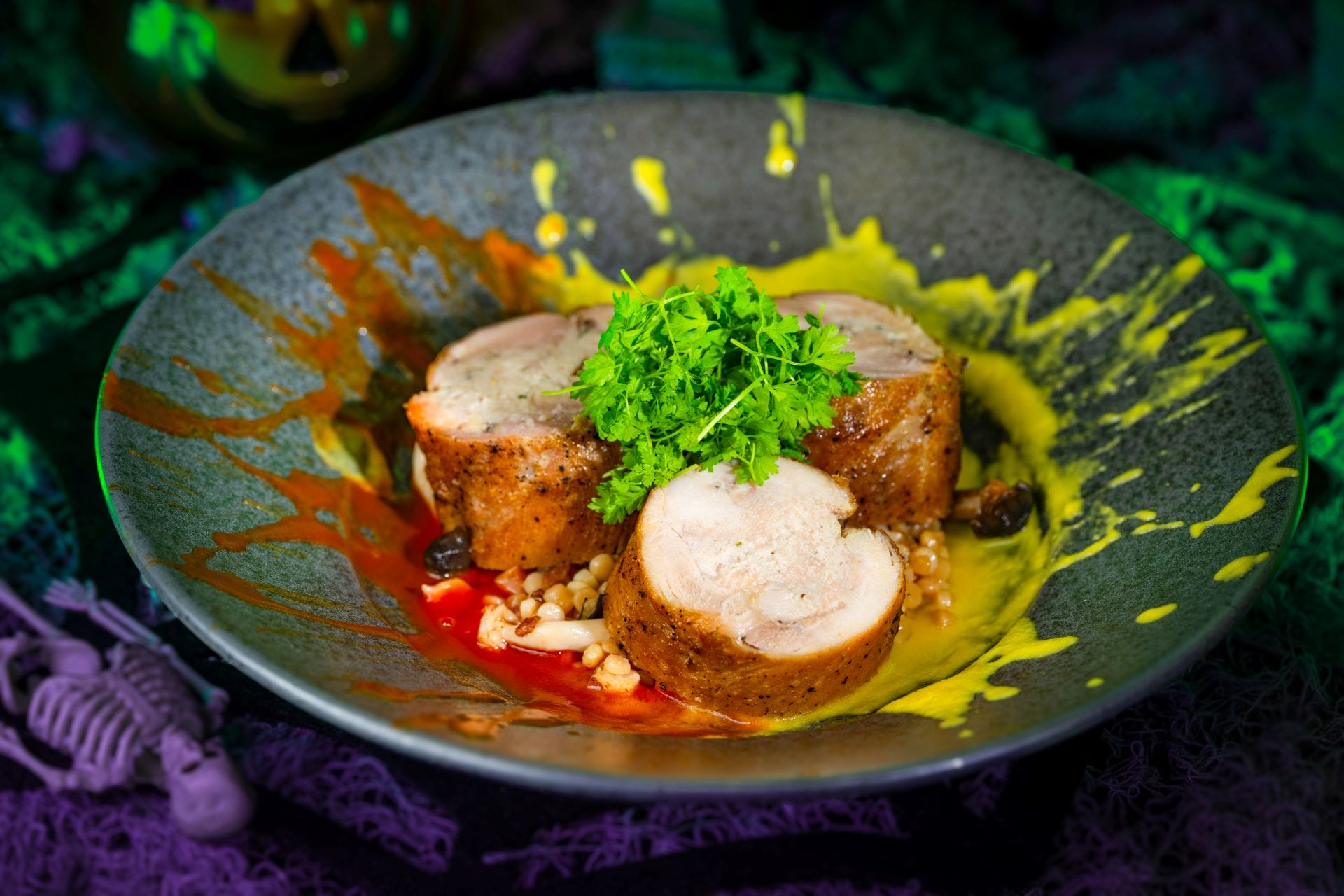 Slices of stuffed chicken roulade on a gray plate with sauces, served at Mickey's Not So Scary Halloween Party 2025.