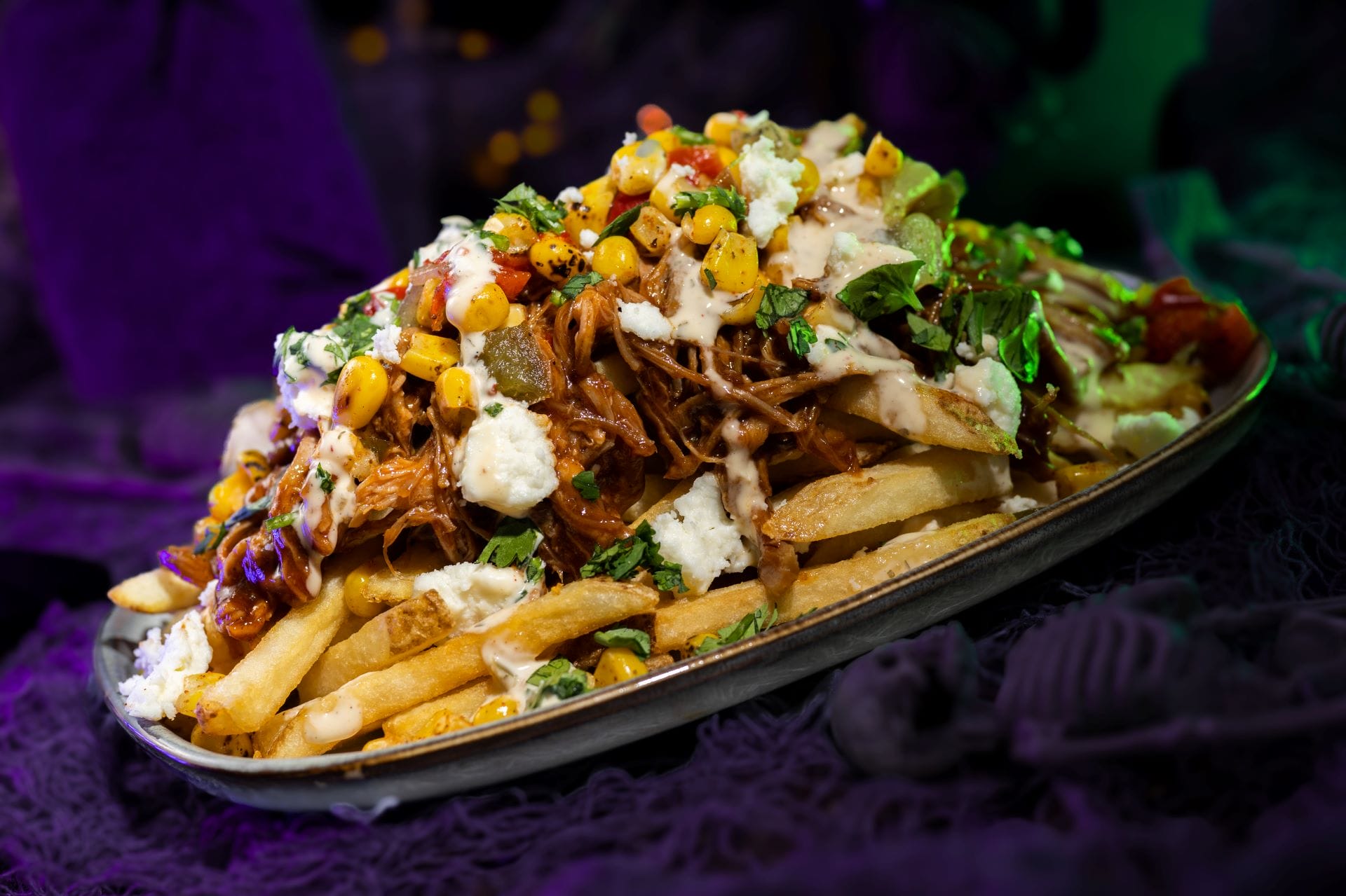 Loaded fries with shredded meat, corn, cheese, and greens—perfect for 2025 Mickey's Not So Scary Halloween Party food and beverages.