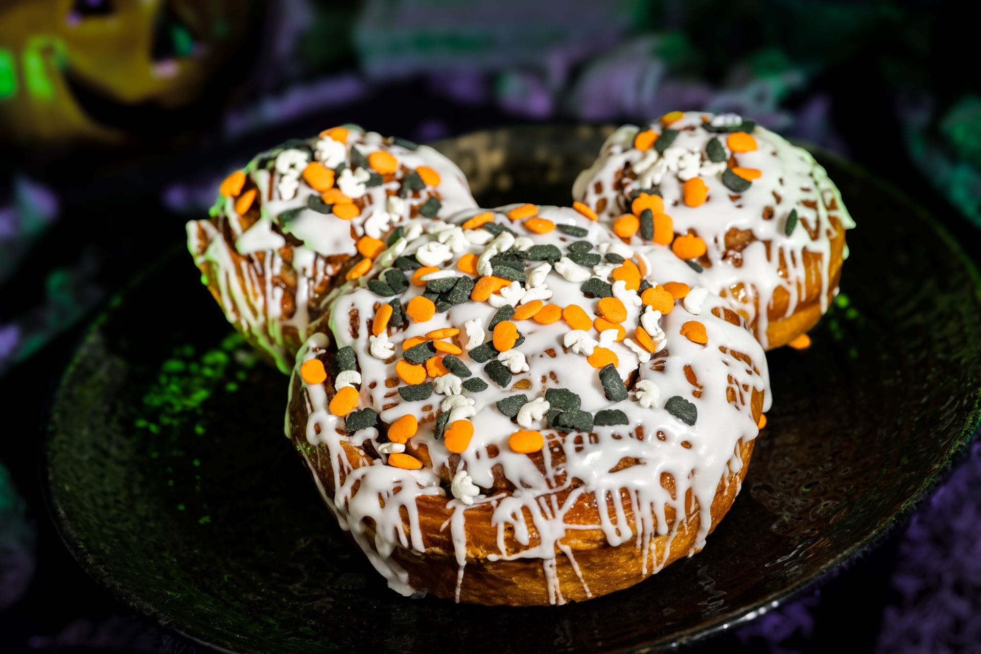 Three cinnamon rolls shaped like Mickey at Mickey's Not So Scary Halloween Party, topped with festive 2025 Halloween sprinkles.