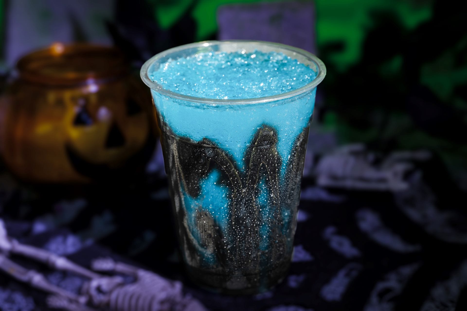 A plastic cup of bright blue and black slushy sits on a spooky table at Mickey's Not So Scary Halloween Party 2025.