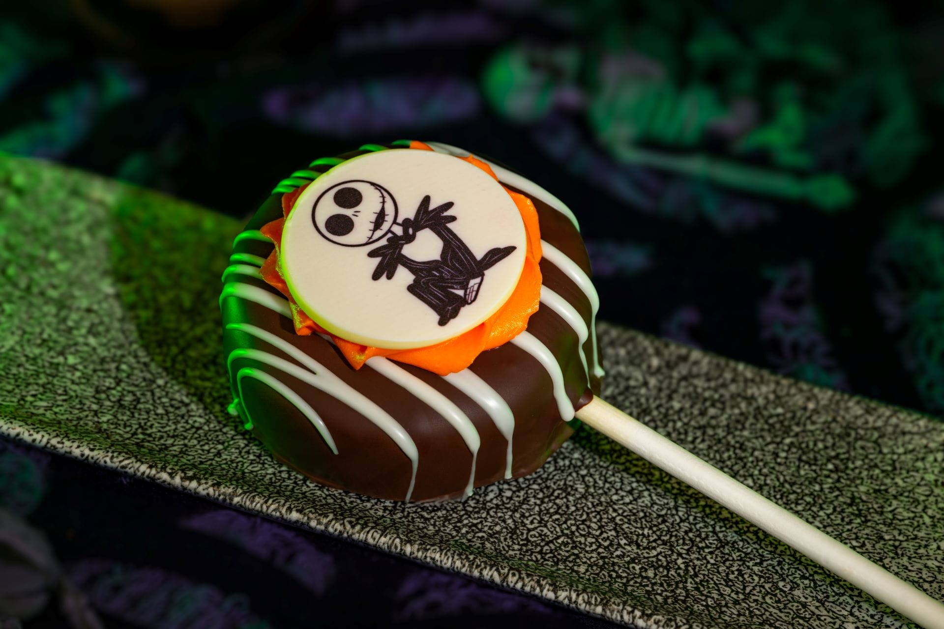 A chocolate-covered treat on a stick, topped with Jack Skellington, perfect for Mickey's Not So Scary Halloween Party 2025.