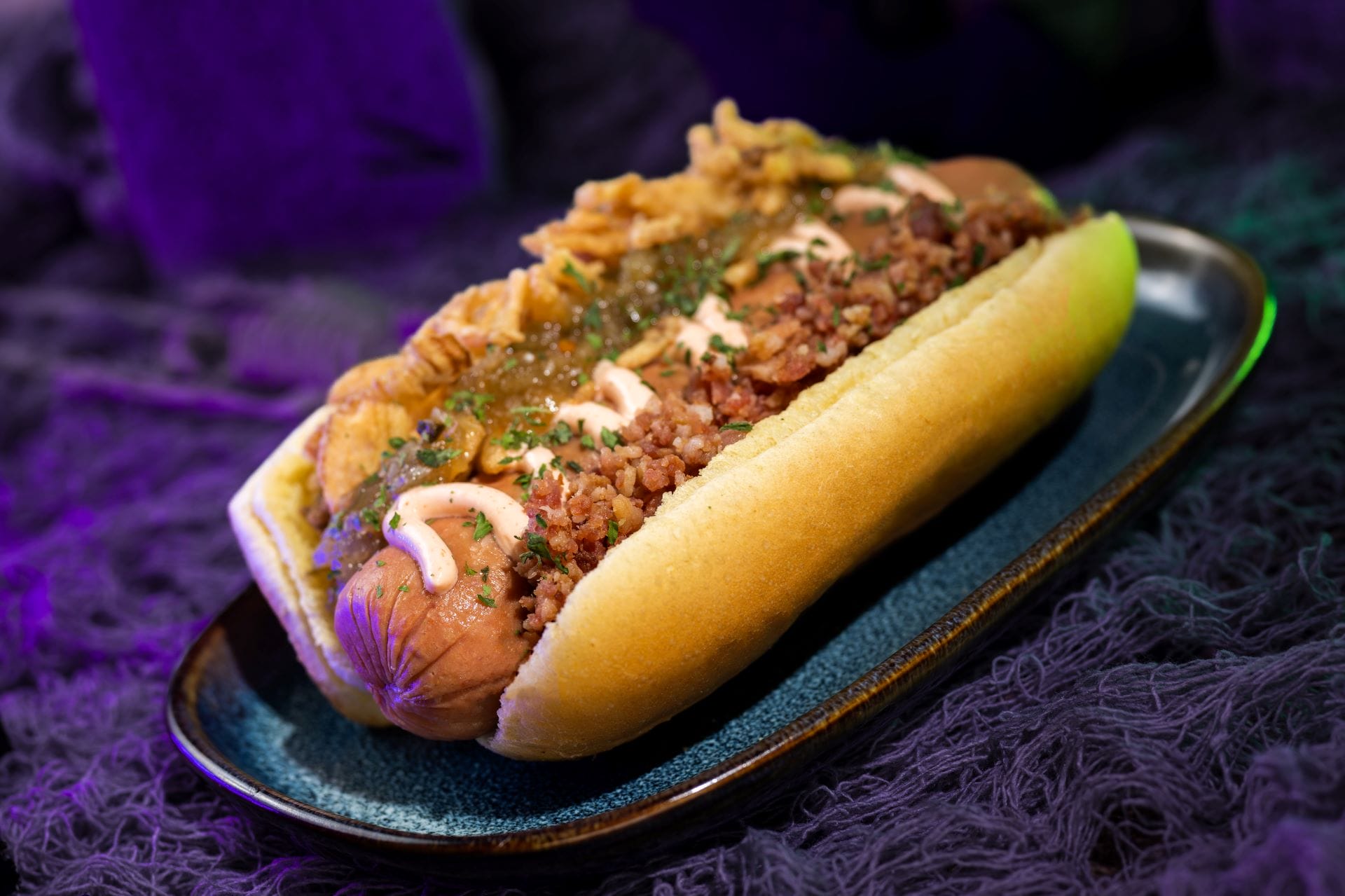 A loaded hot dog with crispy onions, sauce, and relish, perfect for food and beverages at Mickey's Not So Scary Halloween Party 2025.
