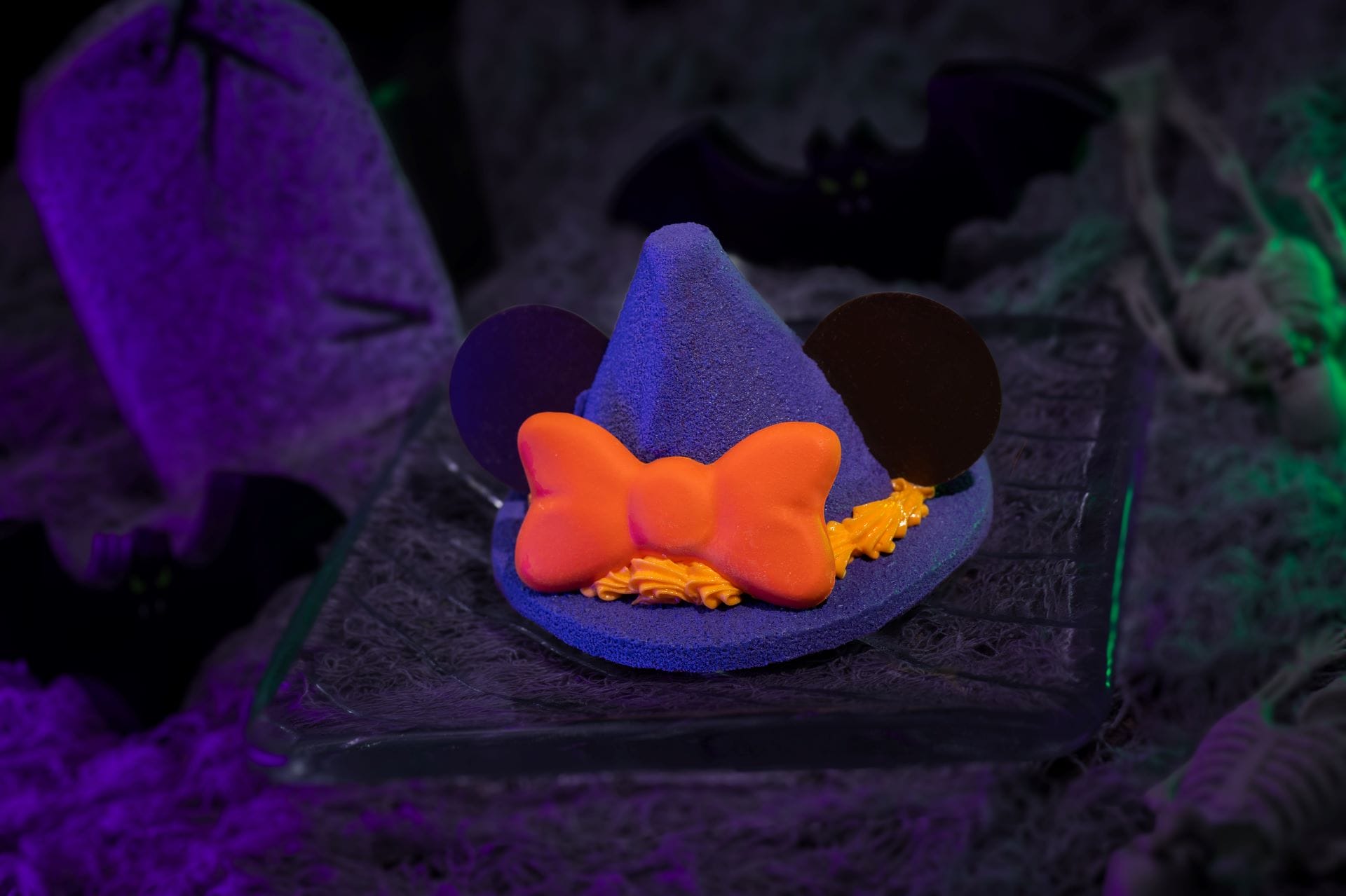 A purple witch hat dessert with Mickey ears and orange bow features at 2025 Mickey's Not So Scary Halloween Party.