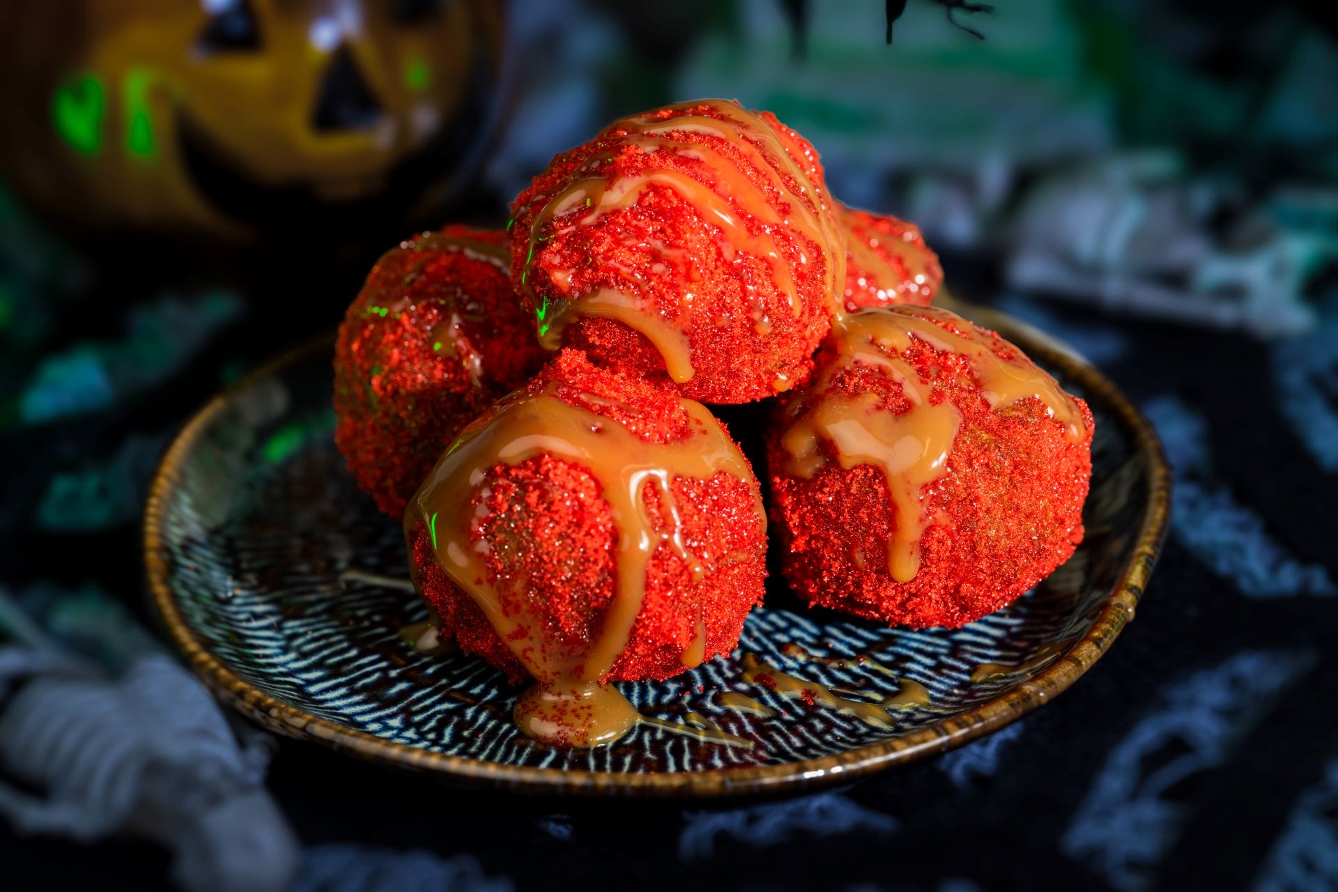 Four round red treats with orange drizzle on a plate, perfect for Mickey's Not So Scary Halloween Party food spread.
