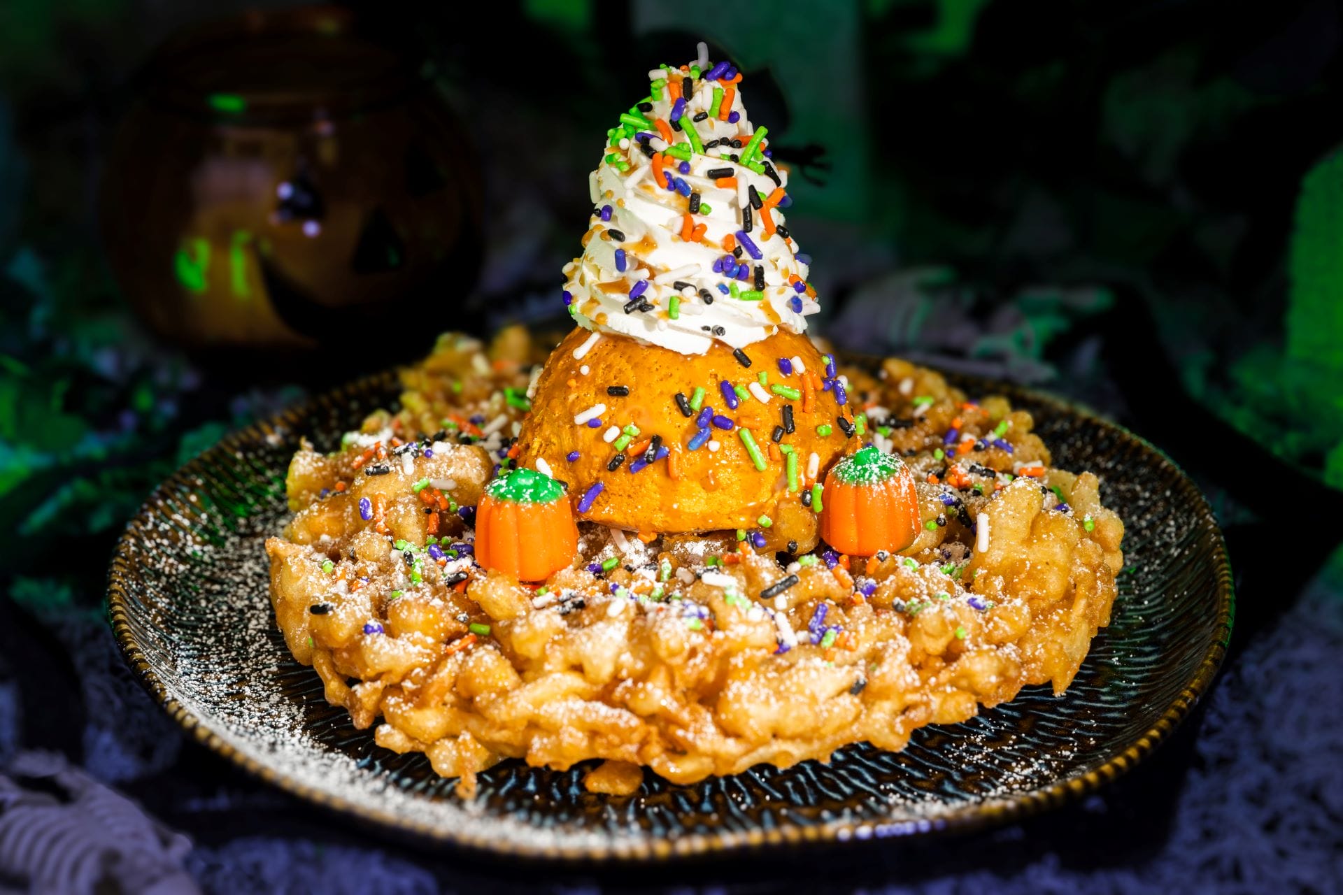 A funnel cake with whipped cream, sprinkles, and candy pumpkins—perfect Halloween food at Mickey's Not So Scary Halloween Party.