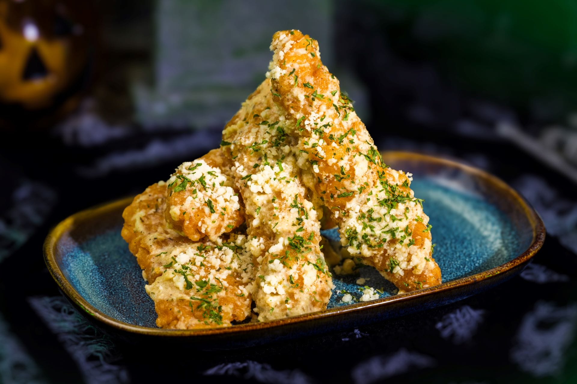 Three crispy breaded chicken tenders with grated cheese and herbs—perfect party food at Mickey’s Not So Scary Halloween Party.
