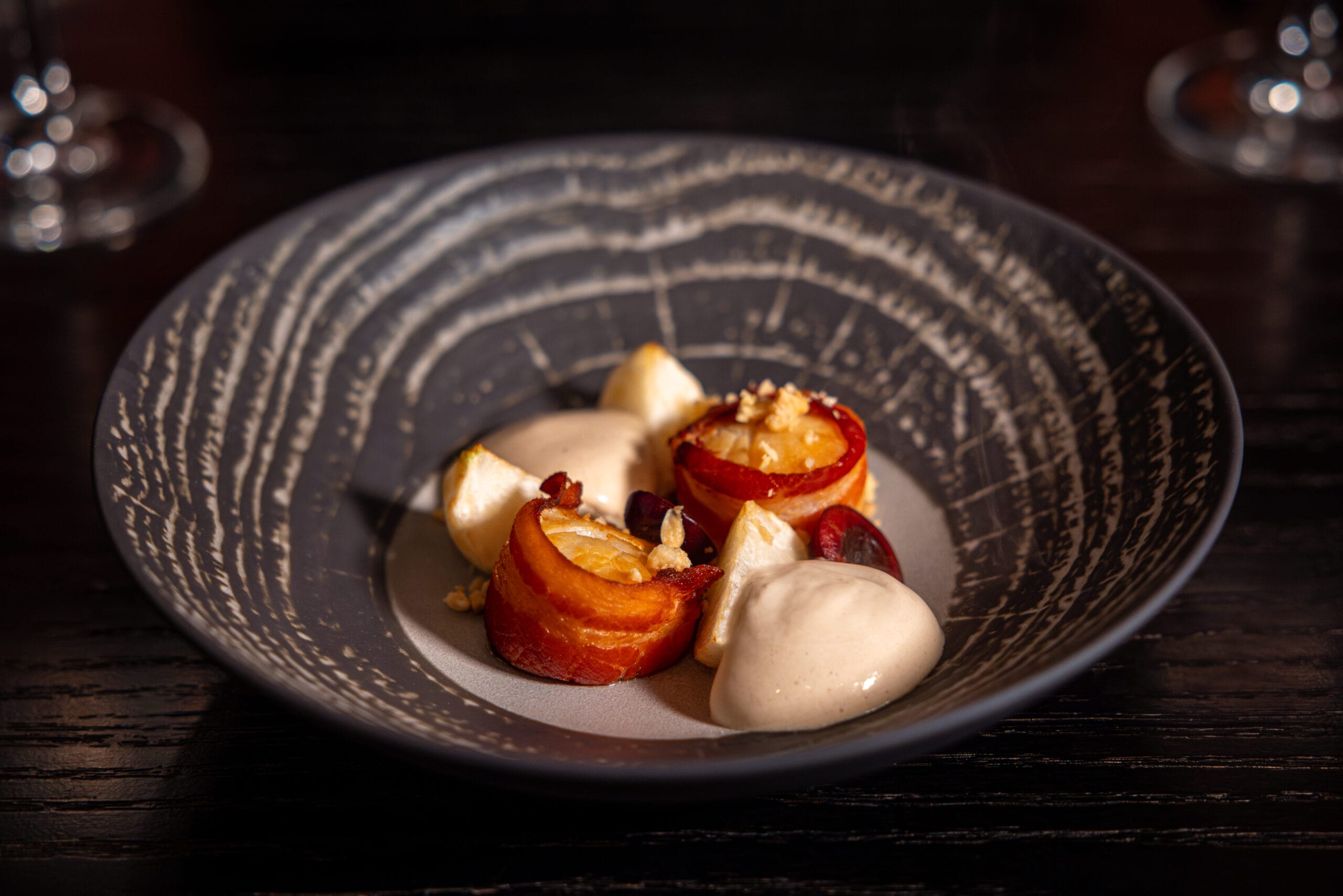 A decorative bowl with artfully plated dessert from Bourbon Steak at Walt Disney World Dolphin Hotel rests on a dark table.