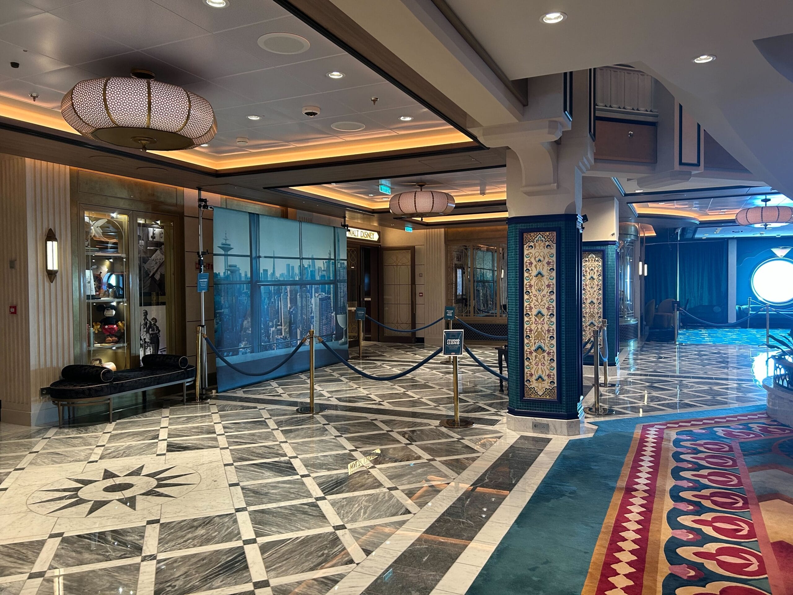 Elegant hotel lobby with marble floors, decorative columns, and a Magic Shot area featuring a cityscape mural.