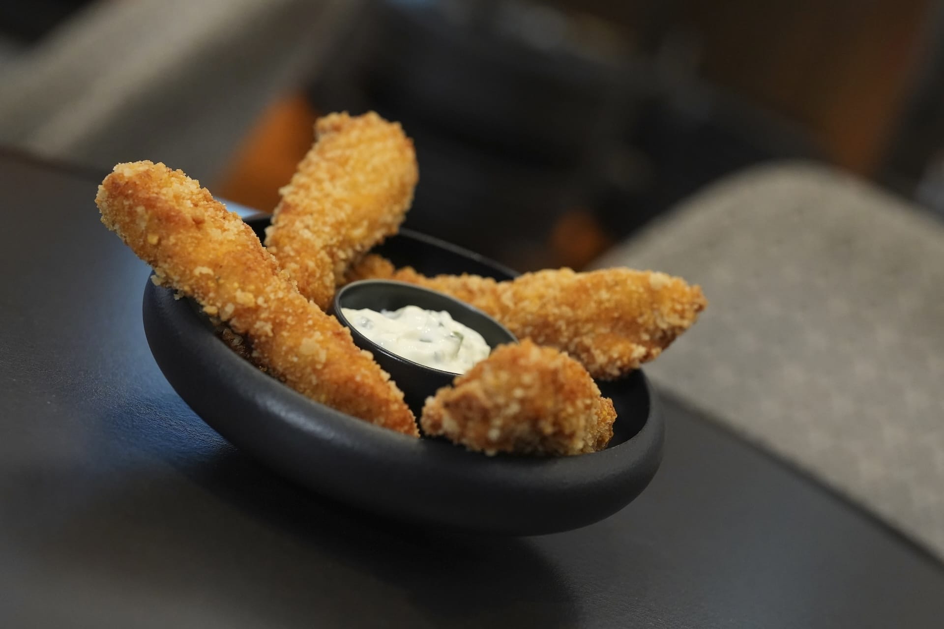 A black bowl with breaded chicken tenders and dipping sauce—perfect Disney Parks food and beverage fare.
