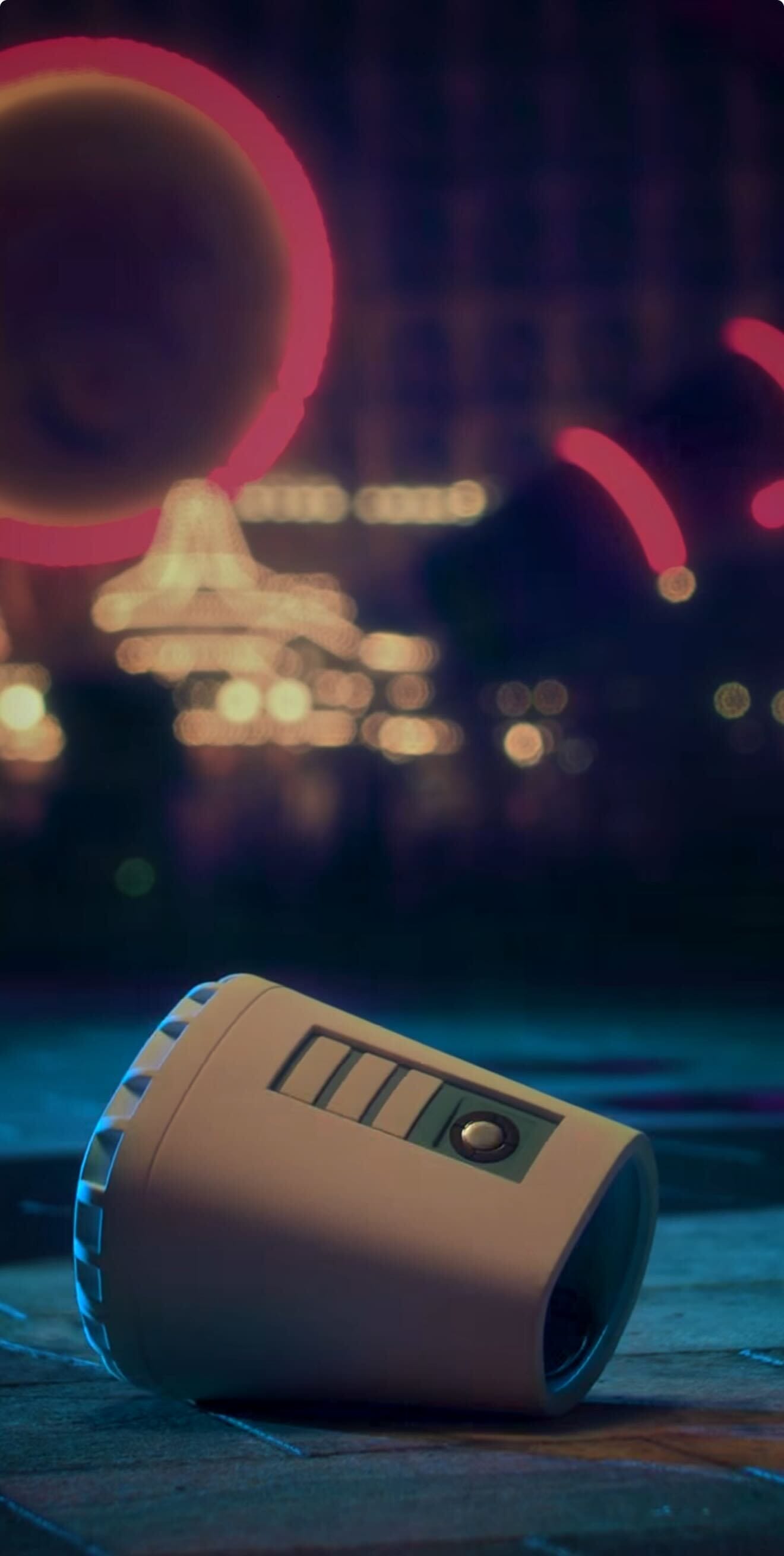 A small robot lies on its side at night as colorful neon lights evoke an Oogie Boogie Bash in the background.