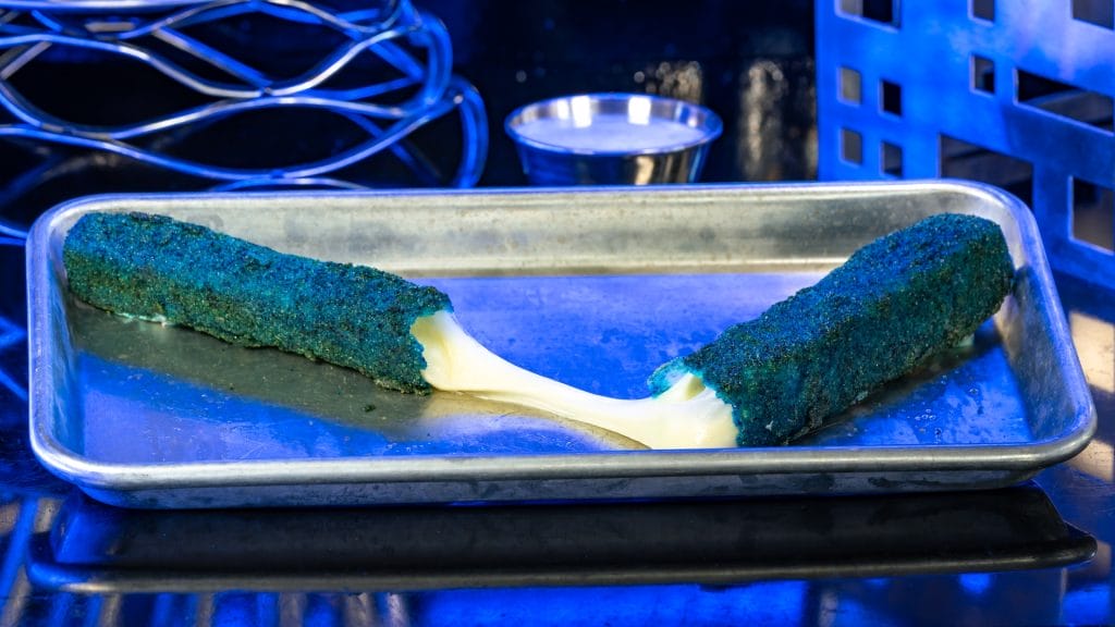 A blue breaded mozzarella stick pulled apart on a tray, this Disney Parks snack is a Food and Beverages favorite.