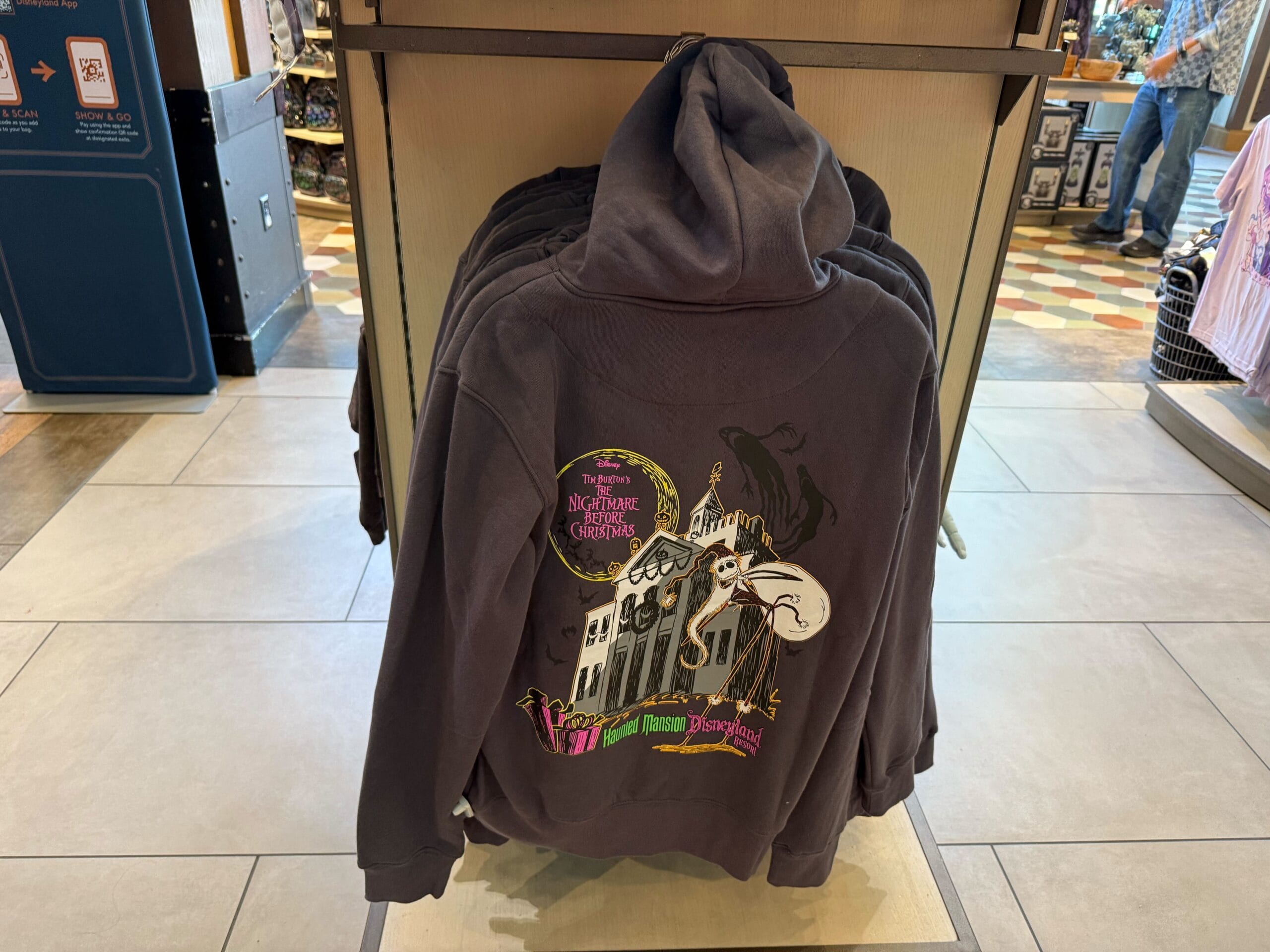 Gray hoodie featuring "The Nightmare Before Christmas" and Haunted Mansion Holiday design, spotted in 2025 Disneyland merchandise.