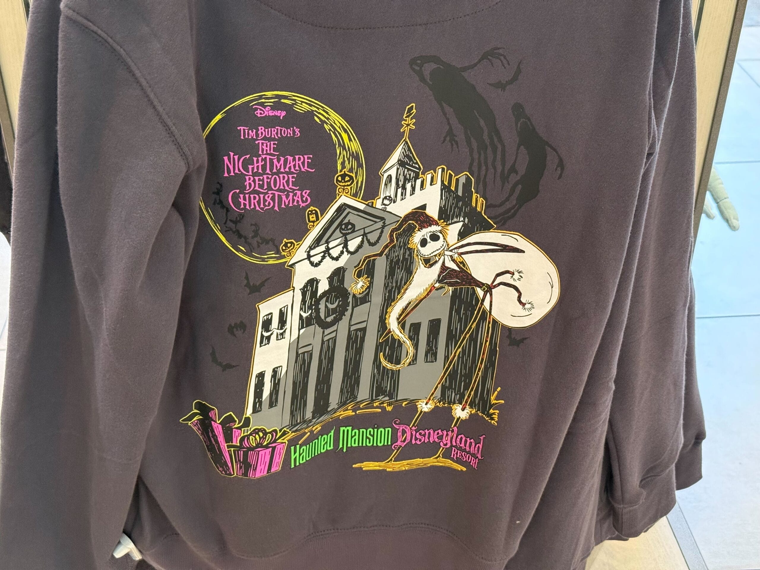 Black sweatshirt with "The Nightmare Before Christmas" and Haunted Mansion Holiday Disneyland 2025 merchandise design.