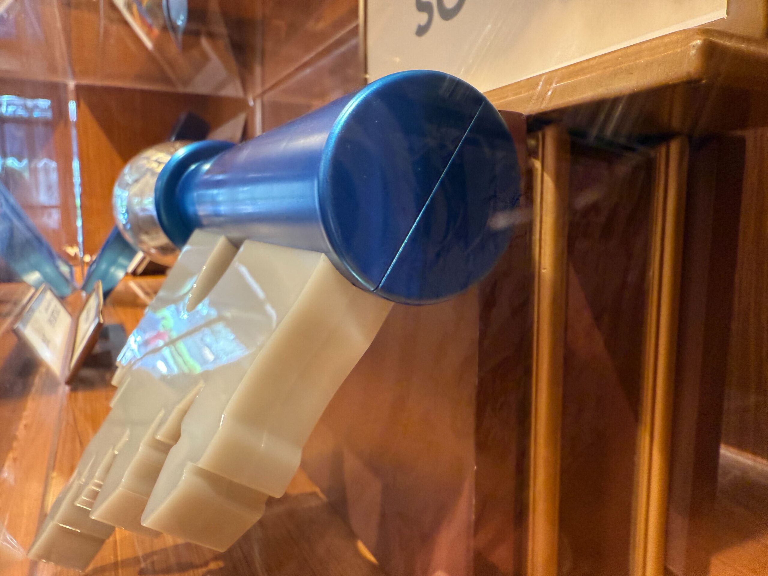 A blue and white model of a space shuttle with a 70th Disneyland collectible key on display in a glass case.