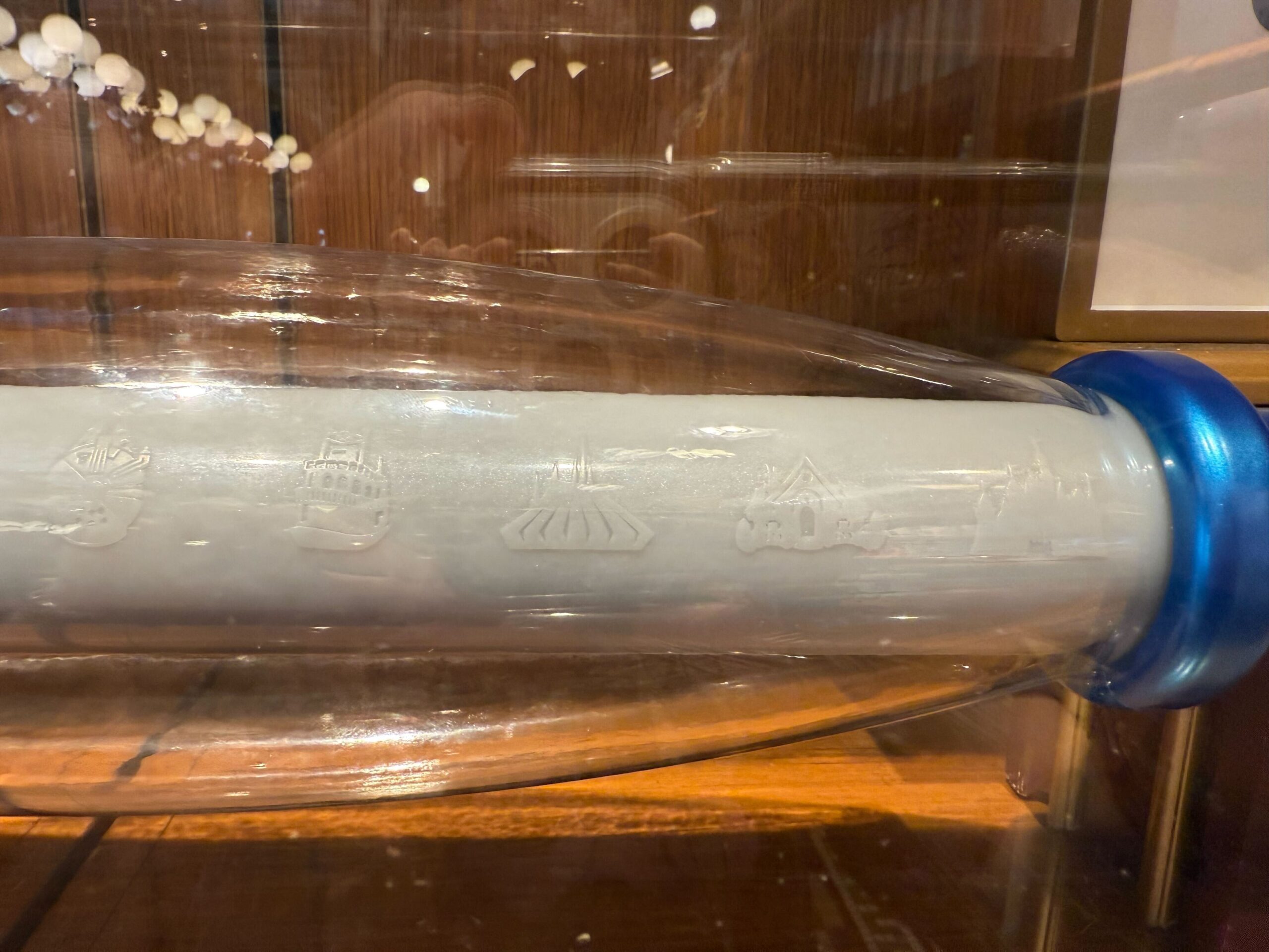 A glass tube with etched ships and vessels, displayed in a museum case—like a 70th Collectible Key at Disneyland.