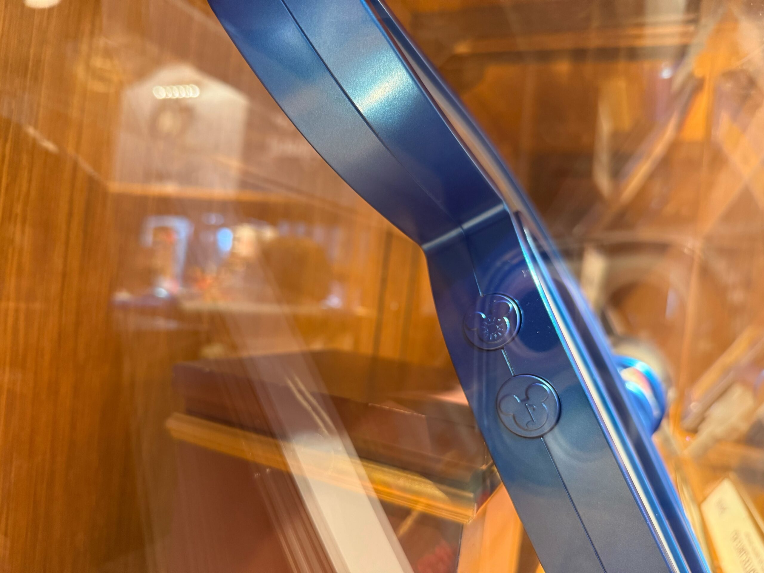 Close-up of a blue metallic 70th Collectible Key with two buttons, set against a blurry wooden background.