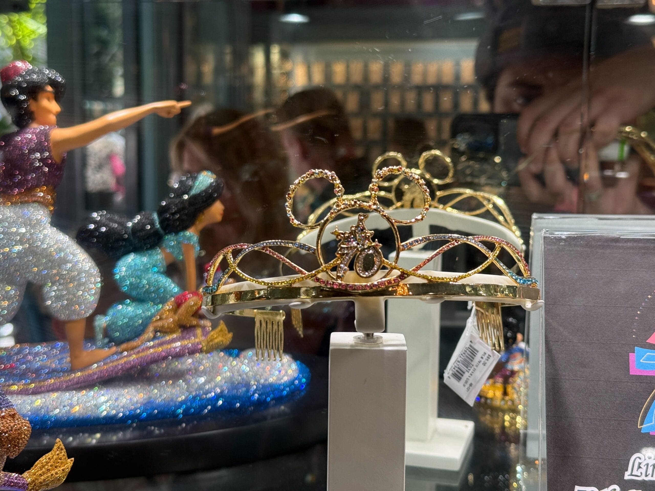 A sparkling Disneyland 70th Anniversary Tiara with Mickey Mouse ears is displayed before Aladdin and Jasmine on a magic carpet.