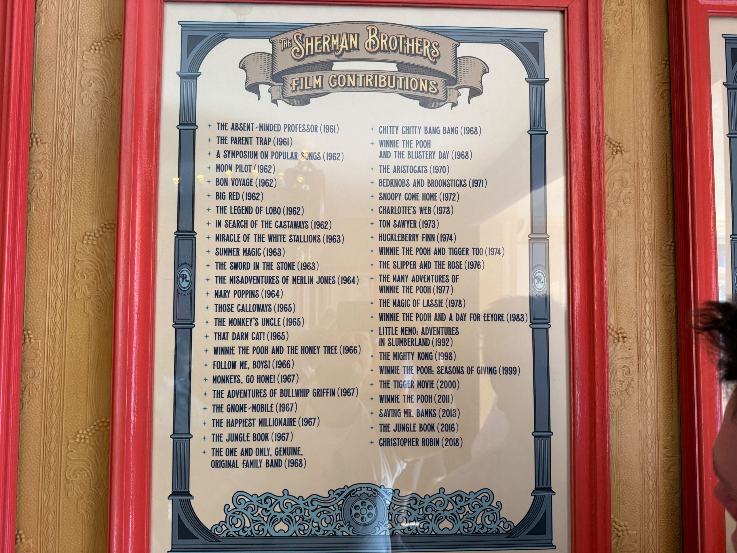 A framed "Sherman Brothers Tribute" film list displayed on a wall with bold red frames.