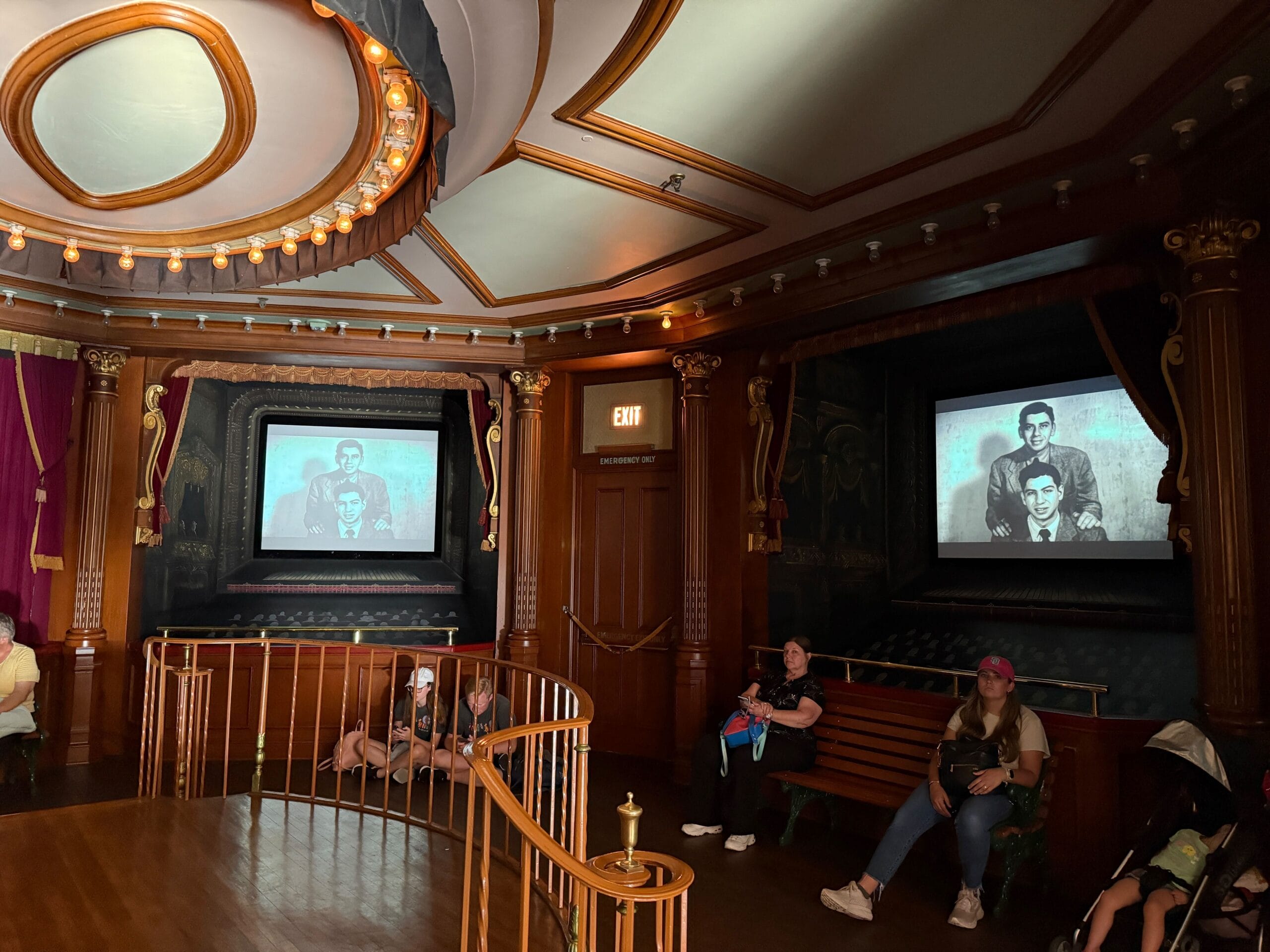 People sit on benches in an ornate Main Street Cinema as vintage photos play during the Sherman Brothers Tribute.