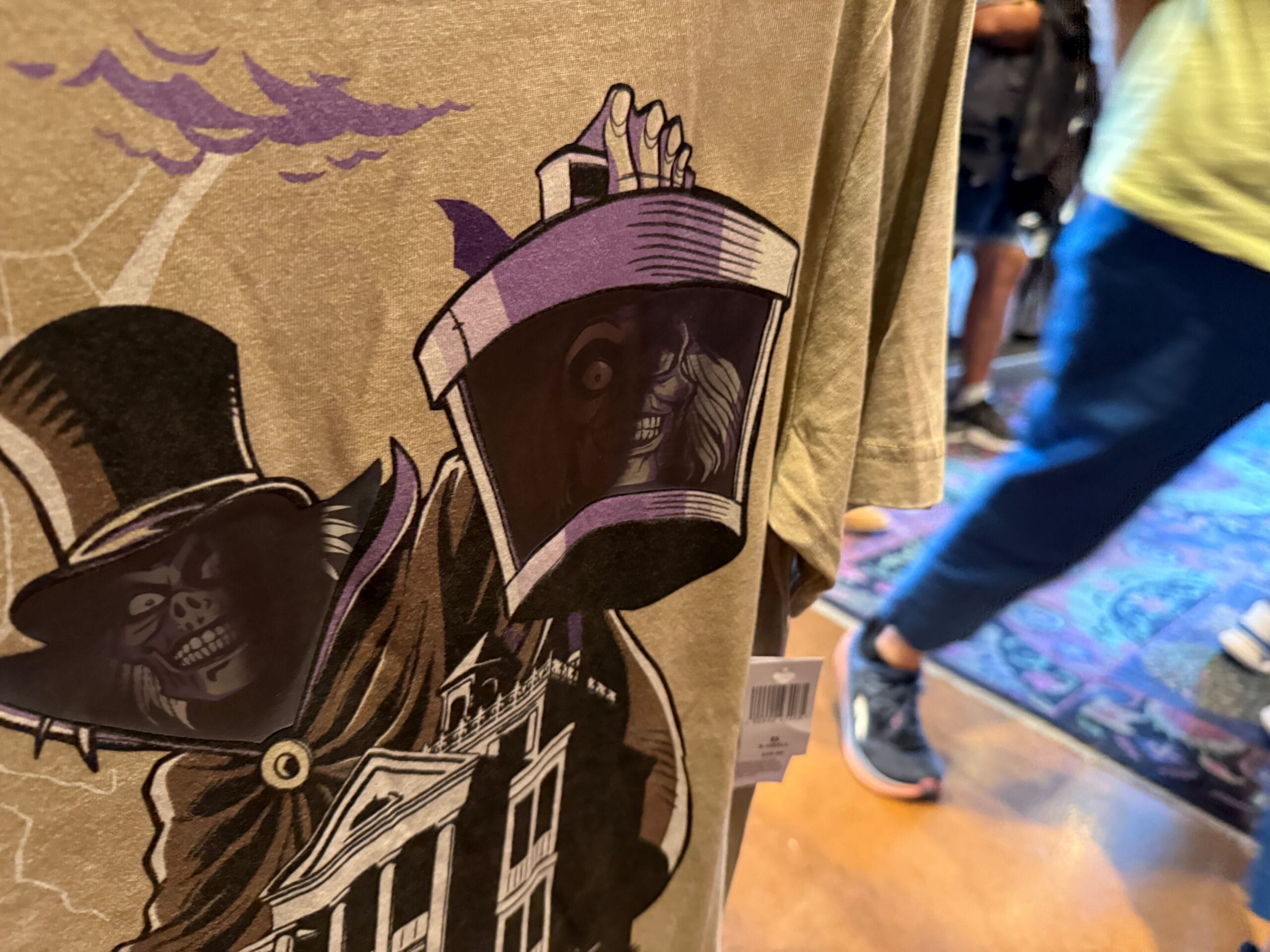 Shirt featuring a spooky skeleton in a top hat, inspired by HM Merchandise at Disneyland, displayed in a store.