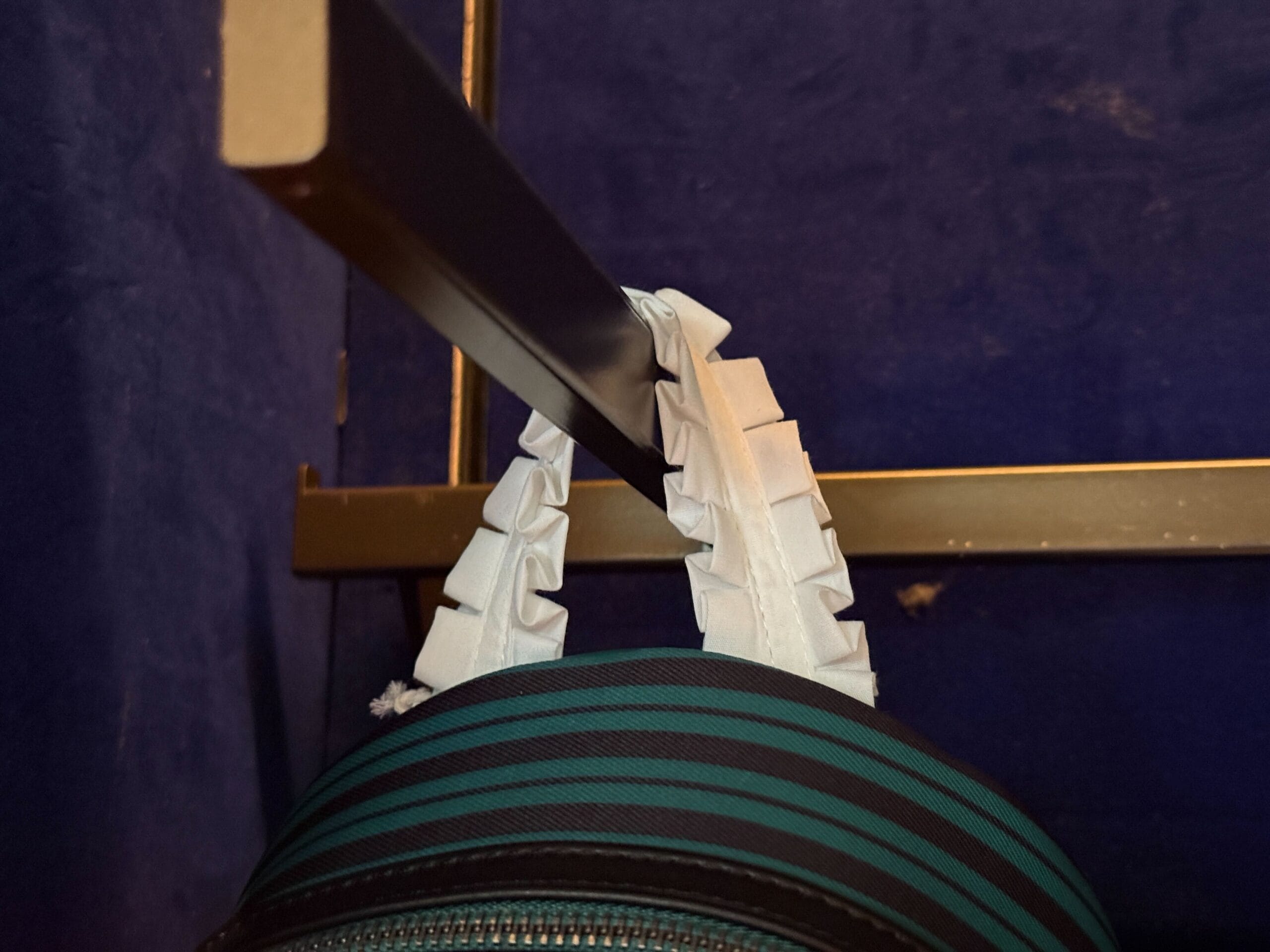 A bag with white ruffled handles hangs on a black metal rail—a touch of Disneyland HM Merchandise charm.