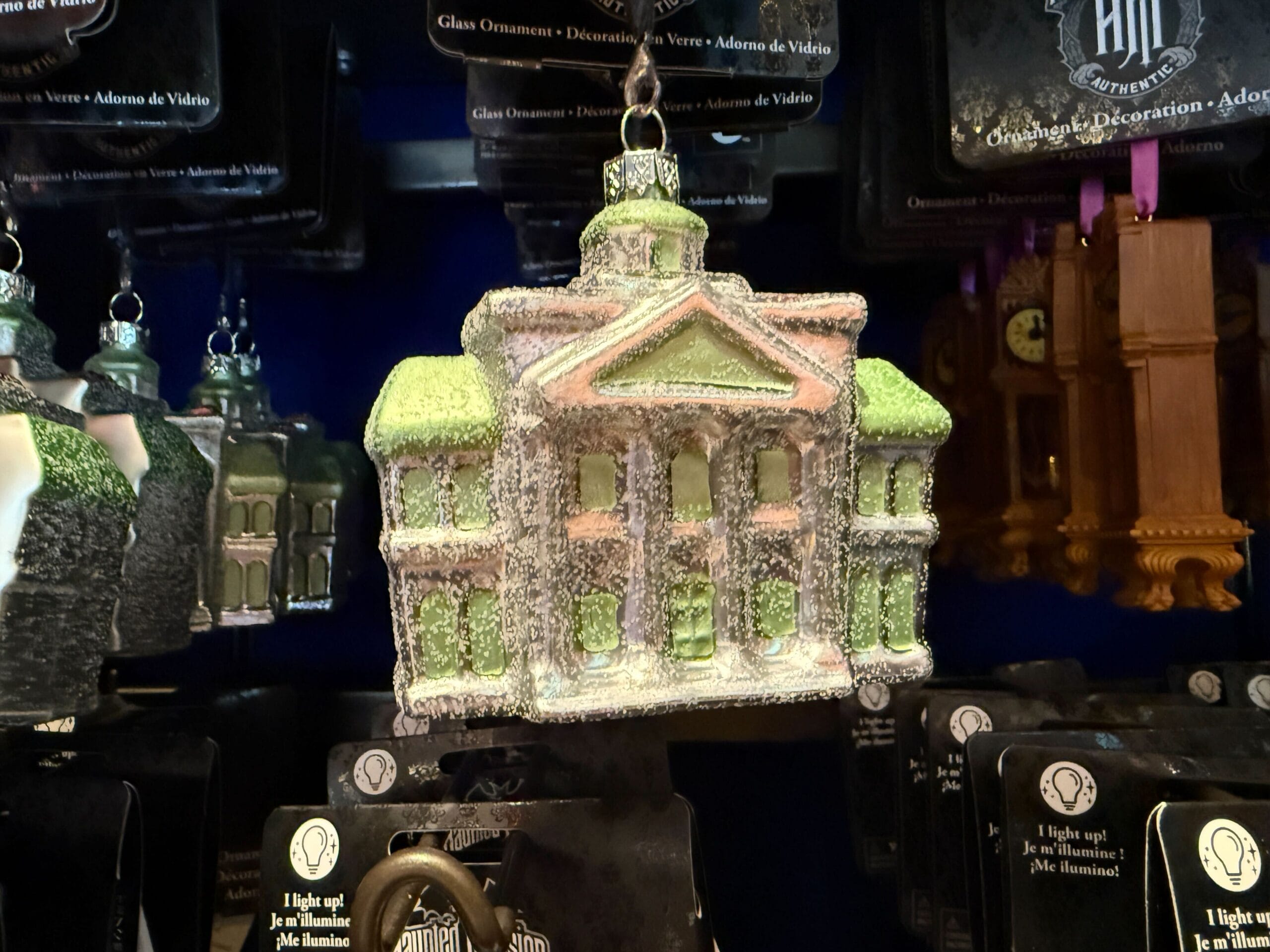 Glass ornament shaped like a green and white mansion, dusted with glitter, perfect for Disneyland merchandise displays.