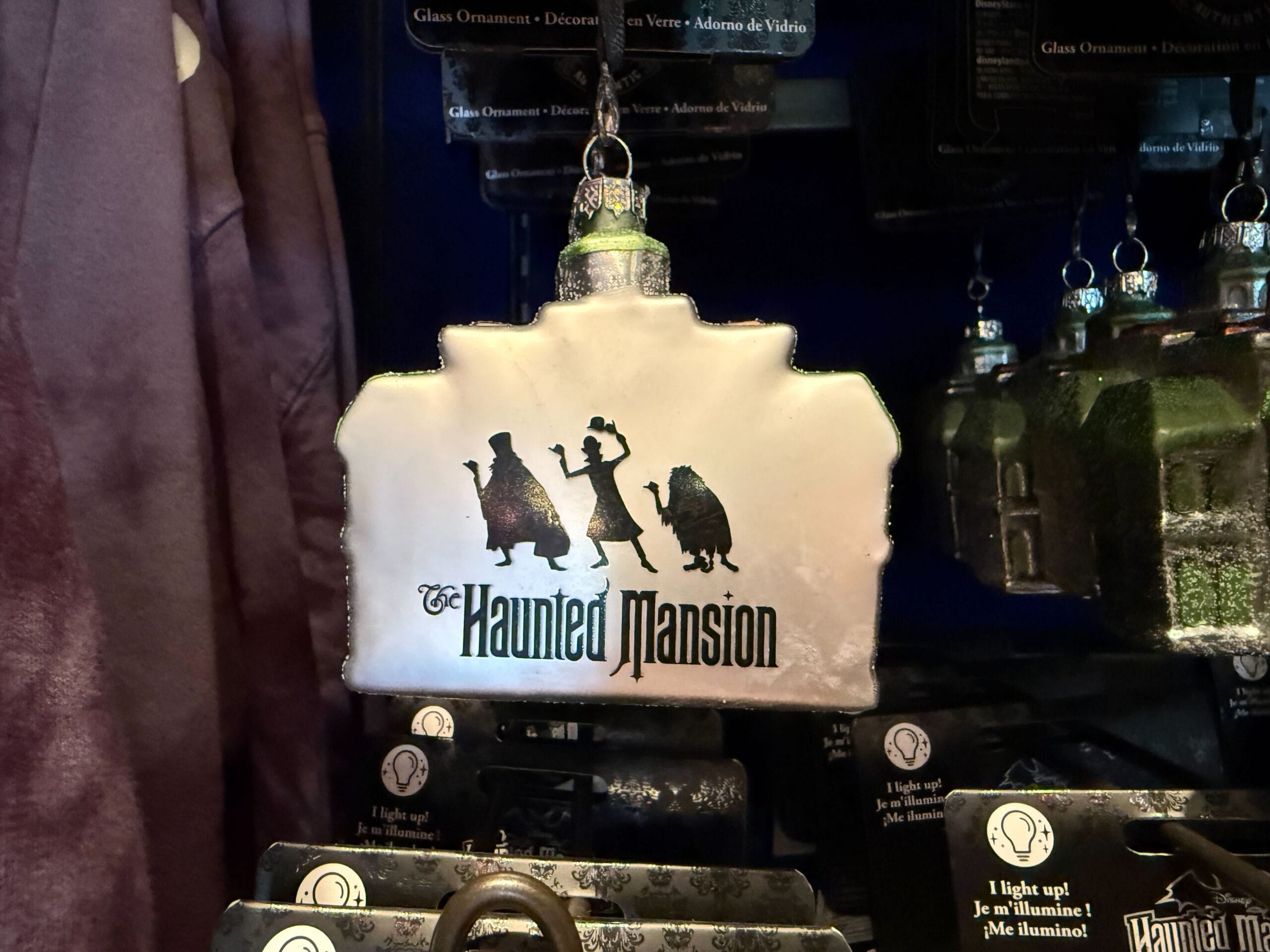 A Haunted Mansion ornament with three ghostly figures and Disneyland’s logo—perfect for HM Merchandise collectors.