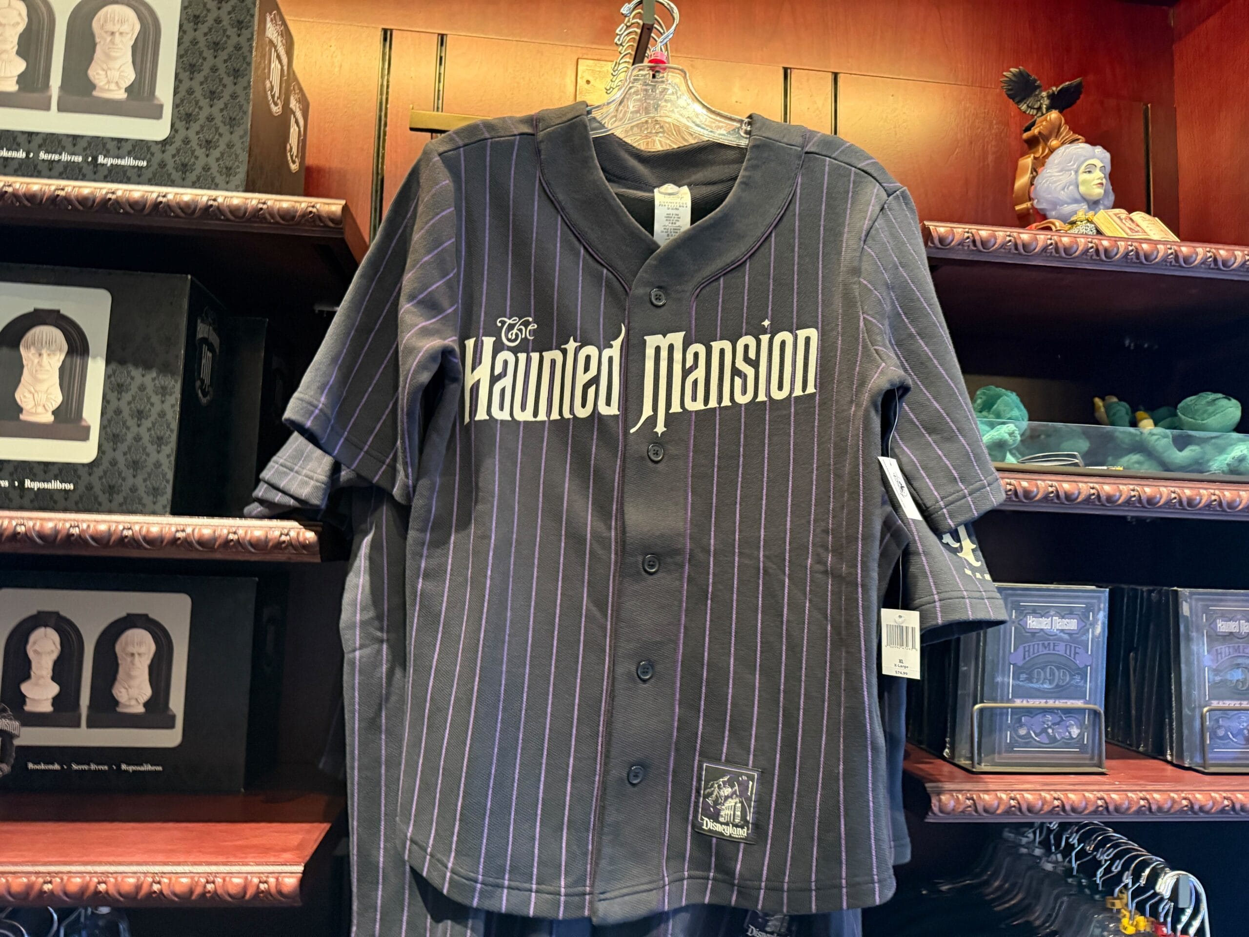 A black pinstripe baseball jersey with "The Haunted Mansion" logo, part of exclusive Disneyland HM Merchandise.