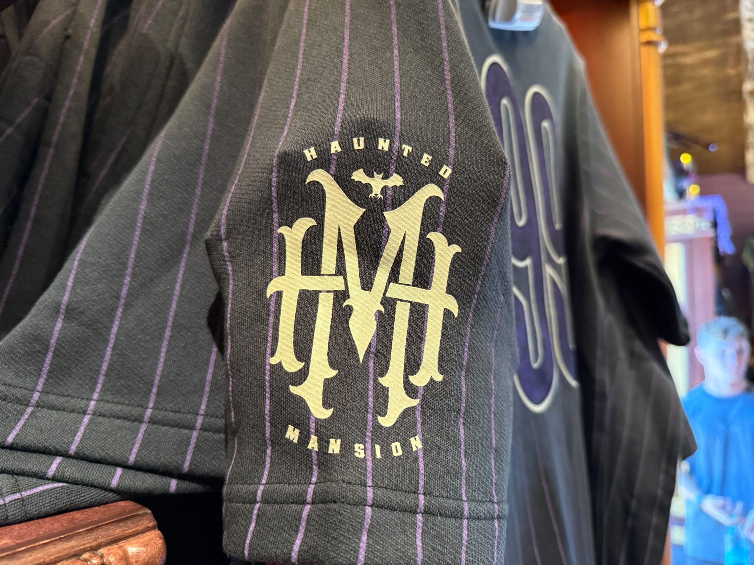 Black shirt with purple pinstripes, featuring a gold "Haunted Mansion" logo—exclusive Disneyland HM Merchandise.