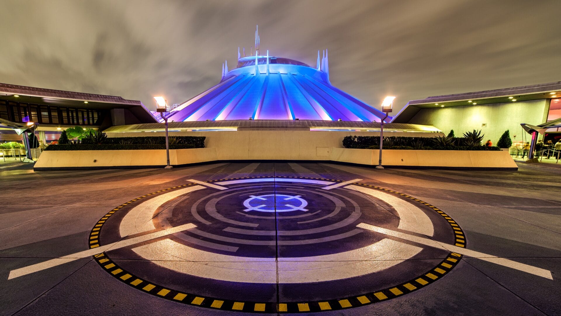 Space Mountain at night, glowing in purple and blue, with a futuristic design—Disneyland Park magic at its finest.