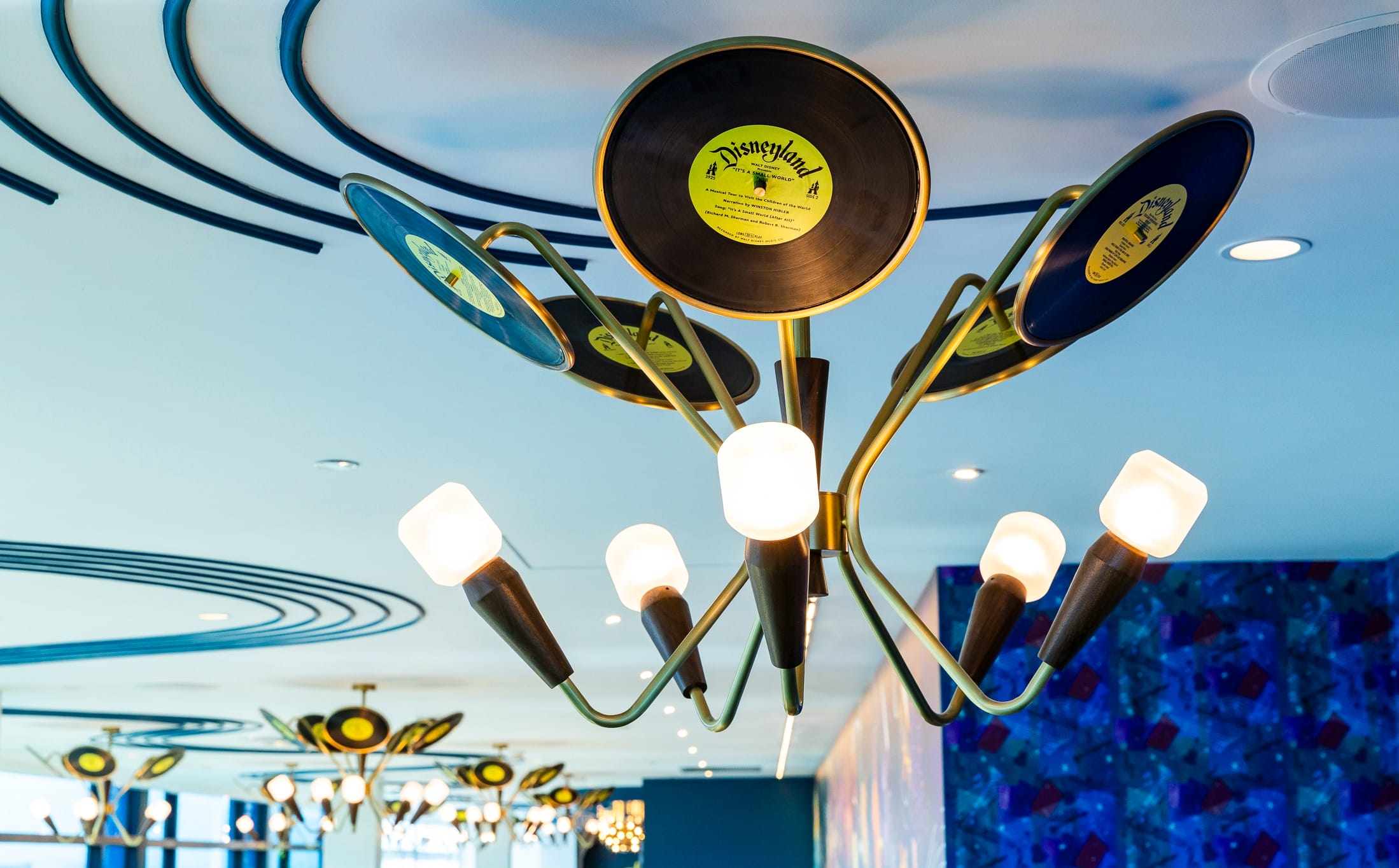 A chandelier with vinyl records hangs from a modern ceiling in the colorful High Key Club at the Disneyland Hotel.