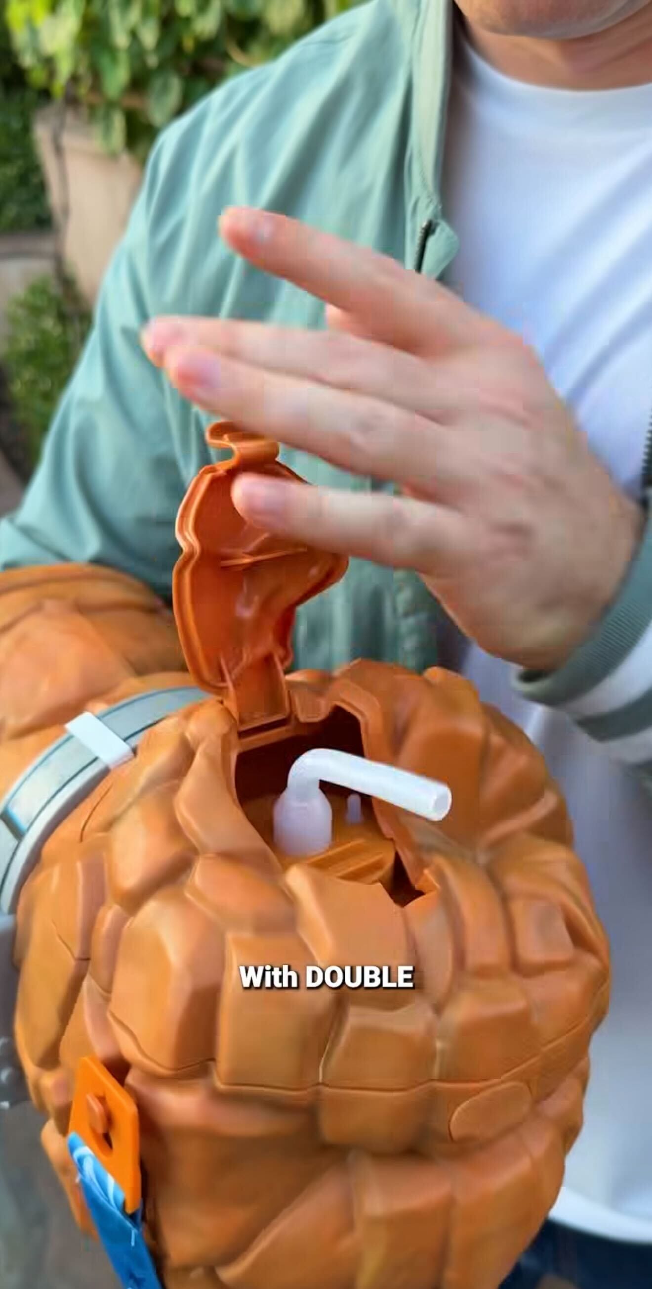 A person opens The Thing Sipper, a rocky fist toy from Disneyland Resort, revealing a white straw inside. The text reads “With DOUBLE.”